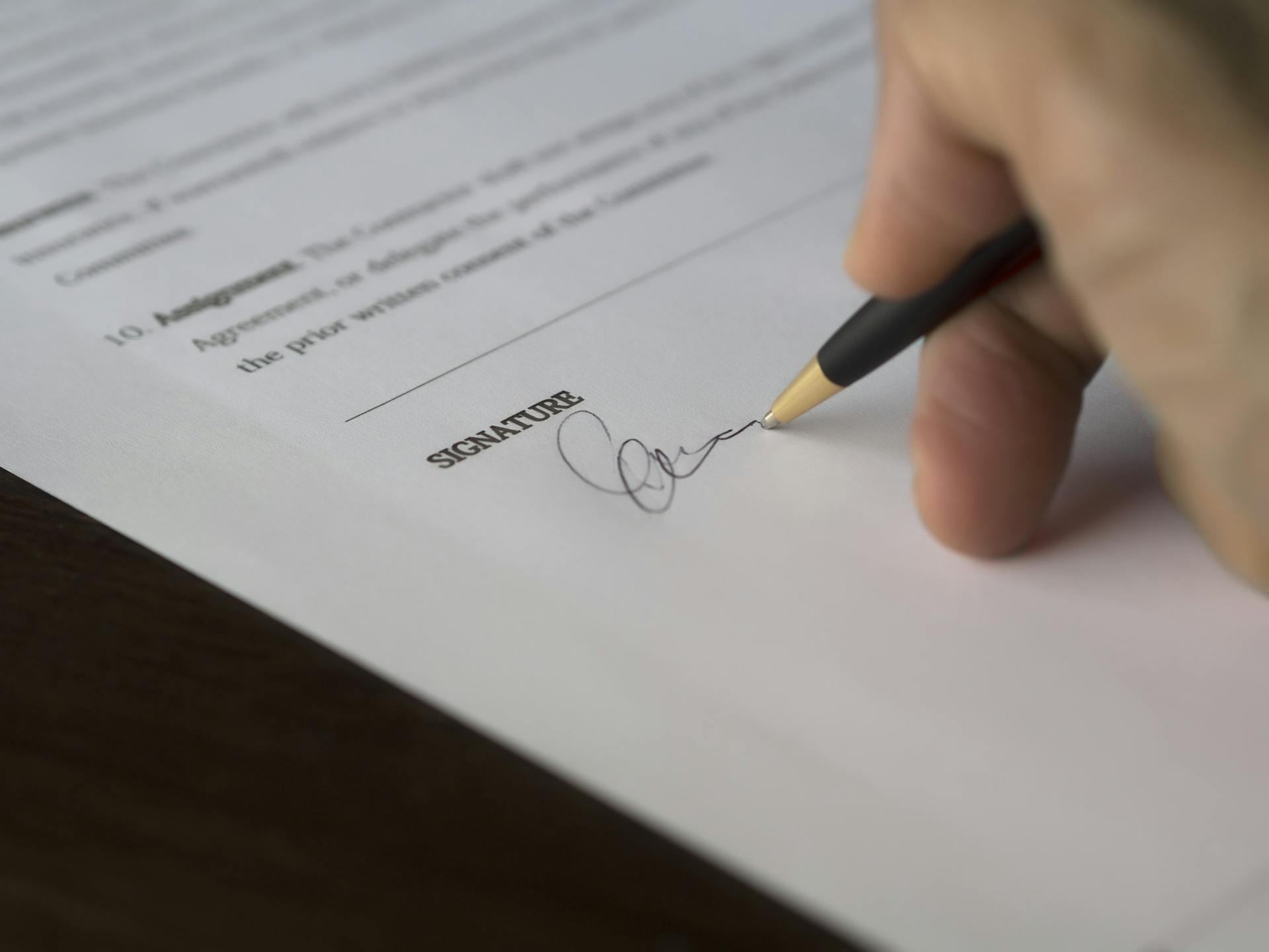 Eine Person, die ein Dokument unterschreibt | Quelle: Pexels