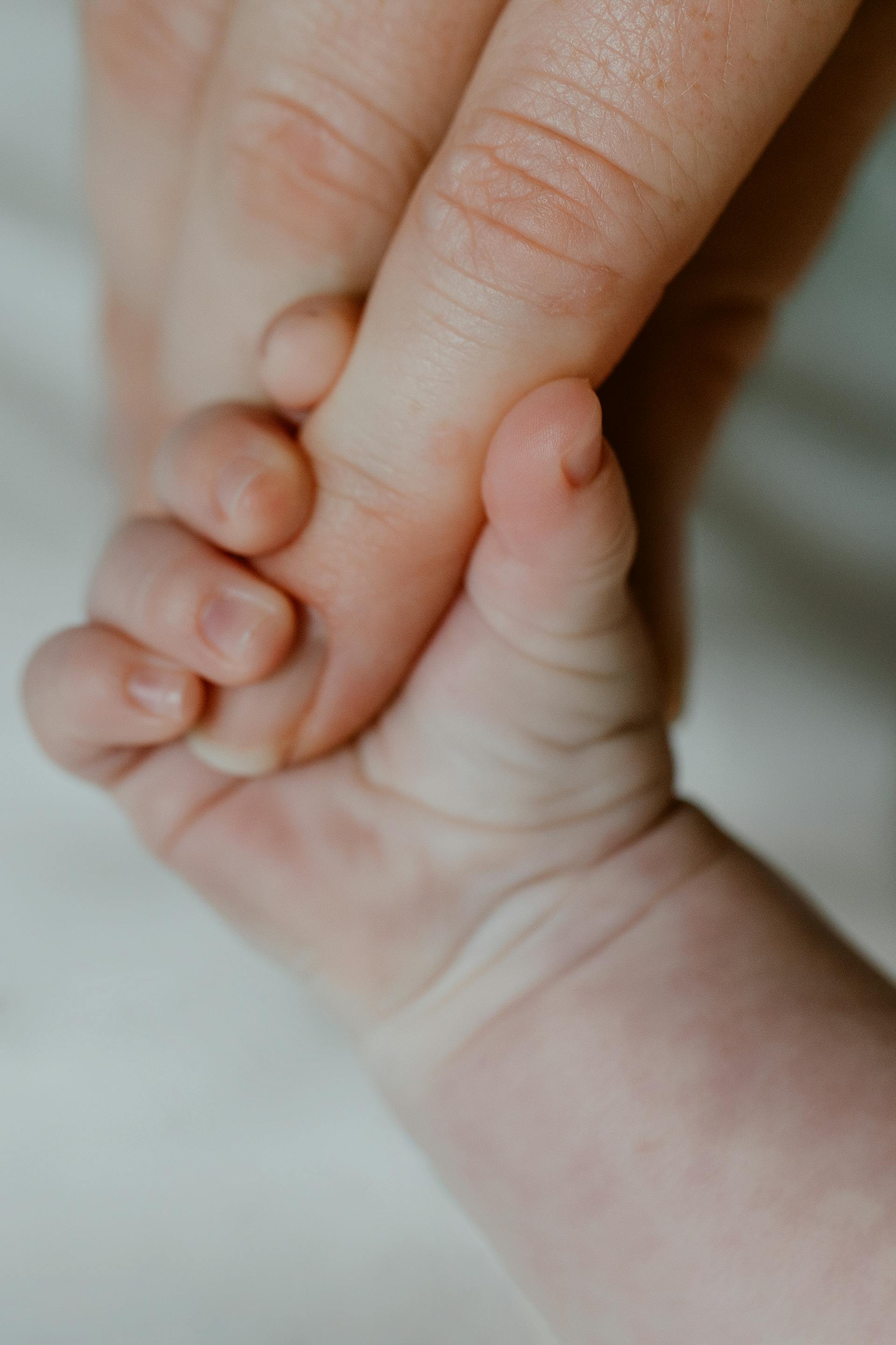 Ein Baby, das den Finger seiner Mutter hält | Quelle: Pexels