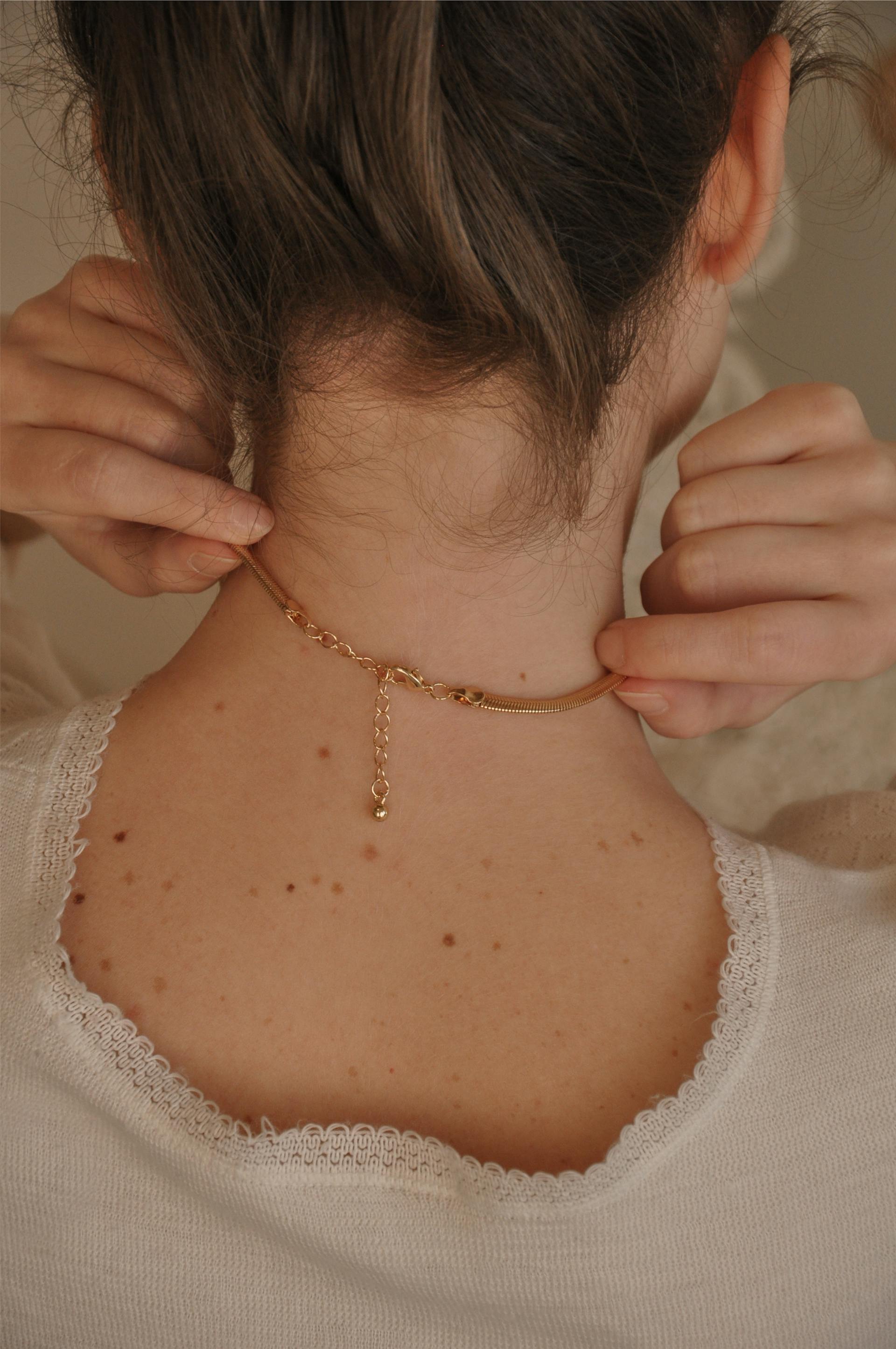 Rückansicht einer Frau, die ihre Halskette berührt | Quelle: Pexels