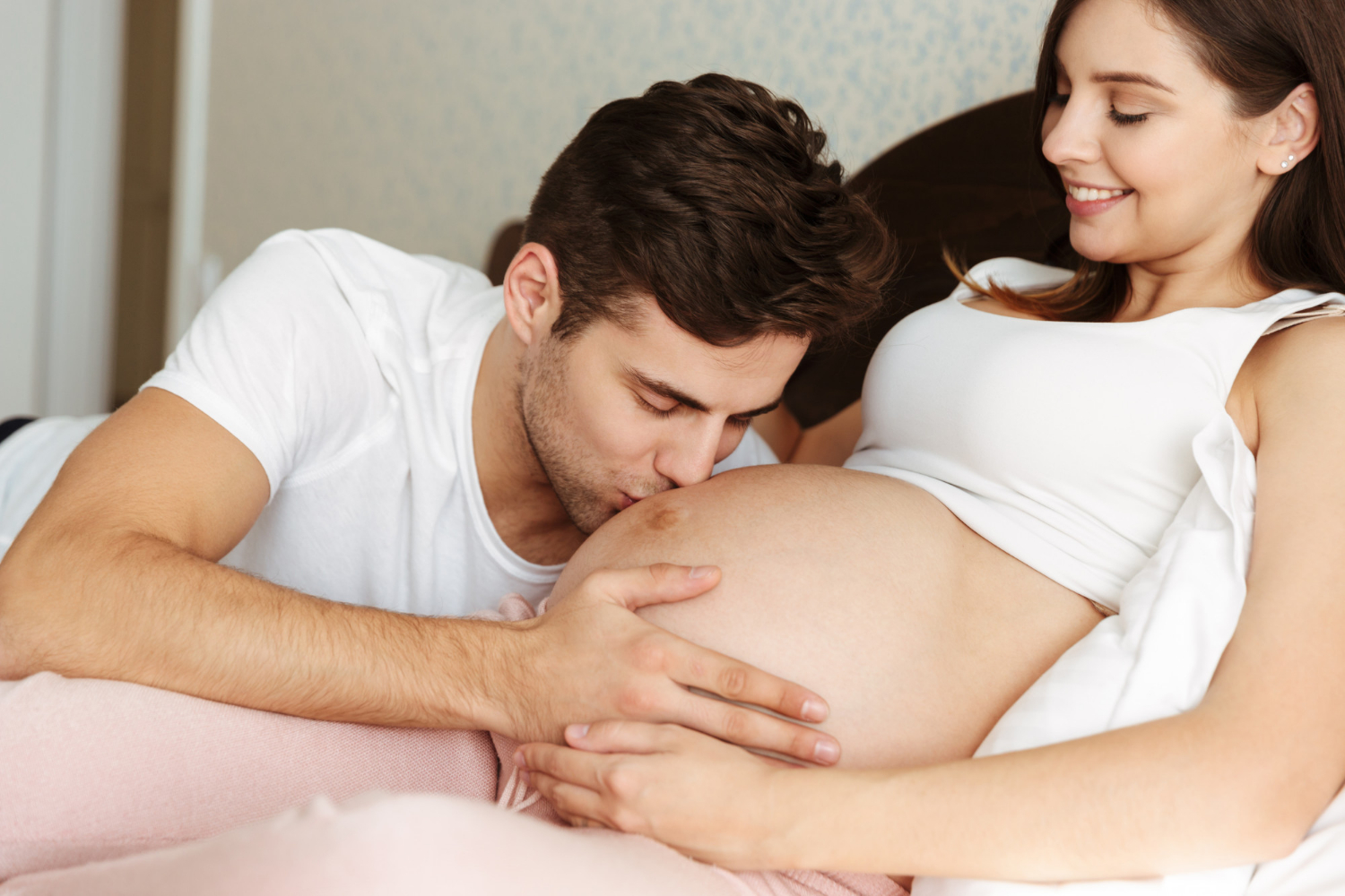 Ein Mann küsst den Babybauch seiner schwangeren Partnerin | Quelle: Freepik