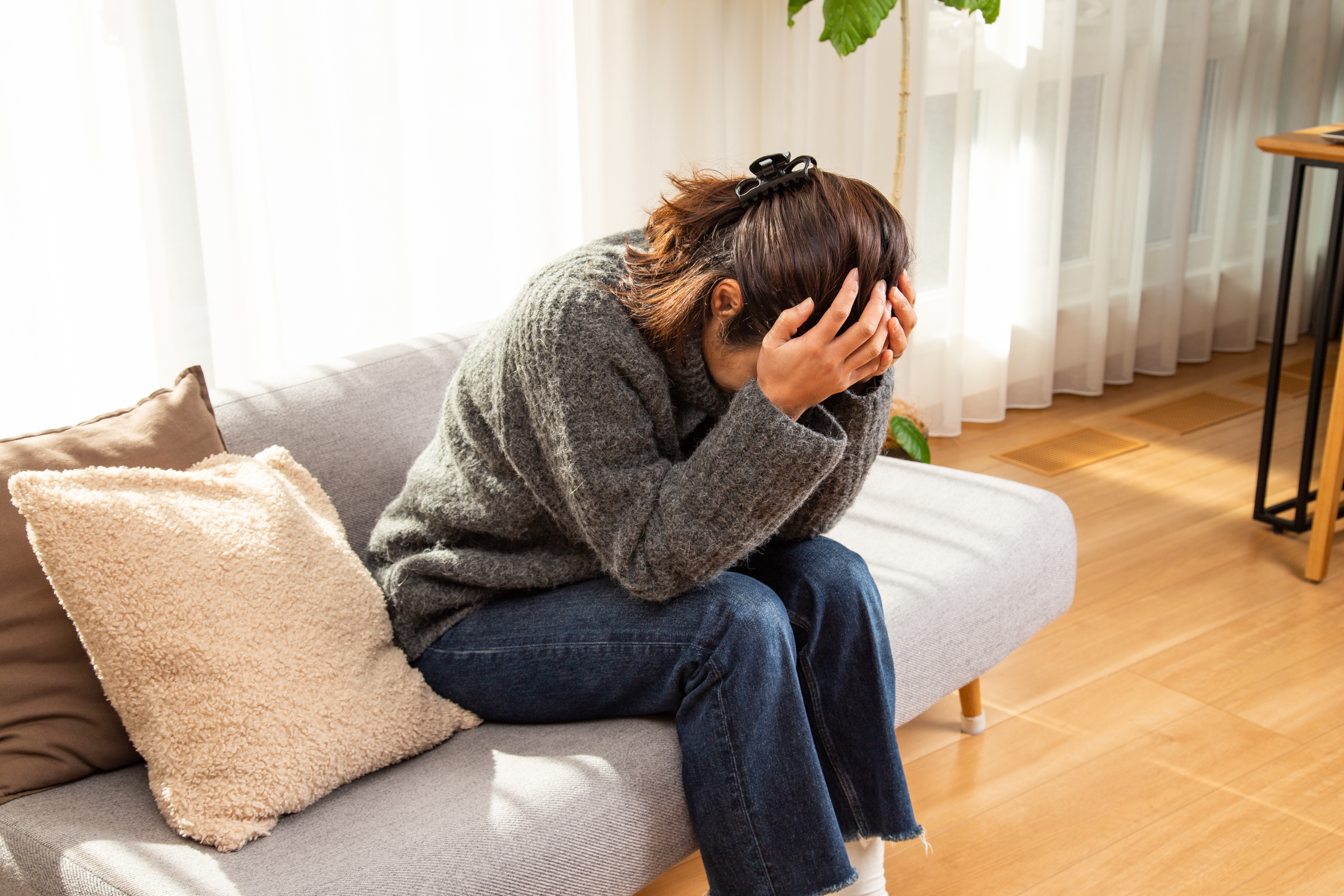 Eine Frau, die sich den Kopf im Wohnzimmer hält | Quelle: Getty Images