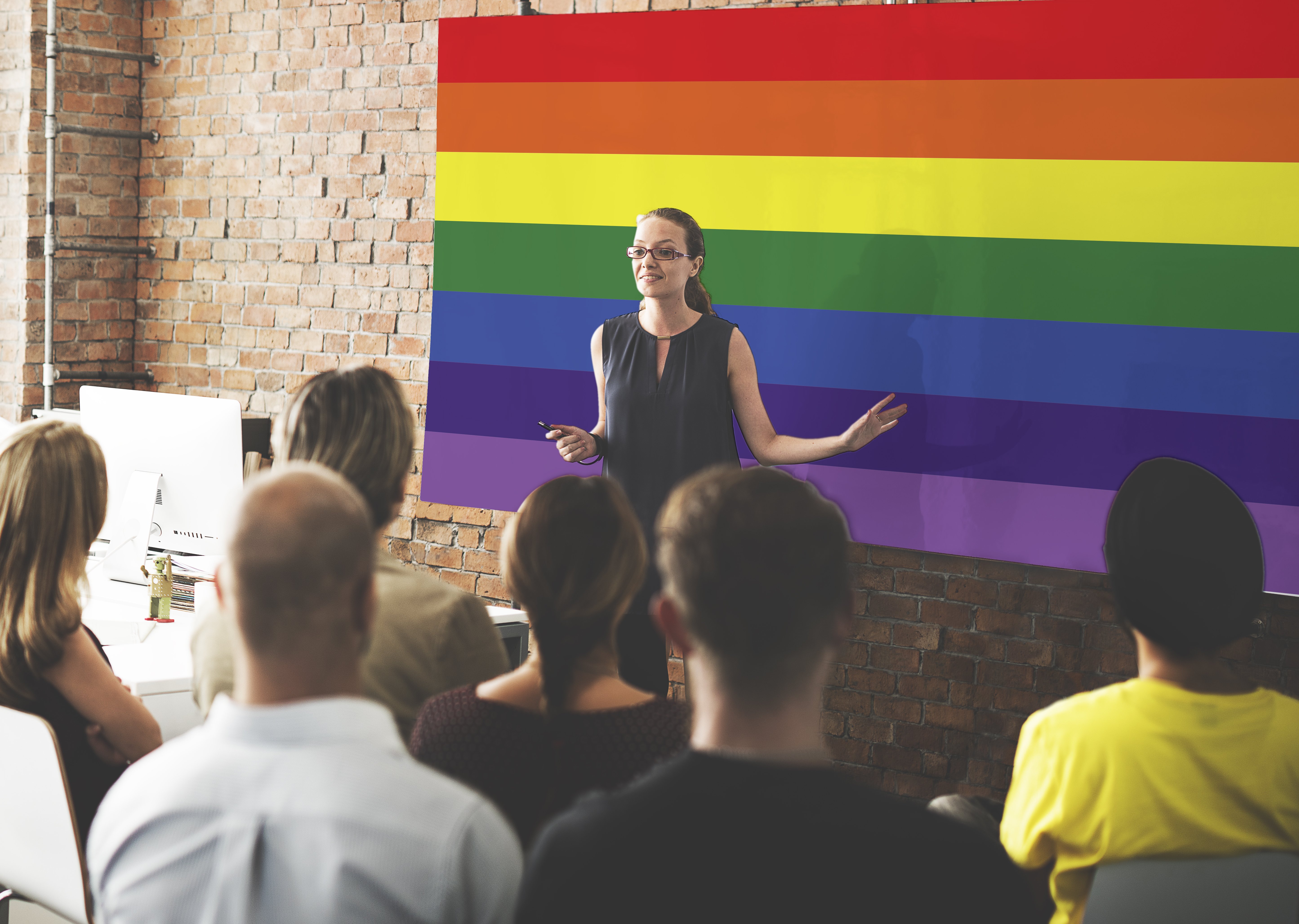 Ein Lehrer steht vor einer LGBTQ+-Flagge. | Quelle: Shutterstock