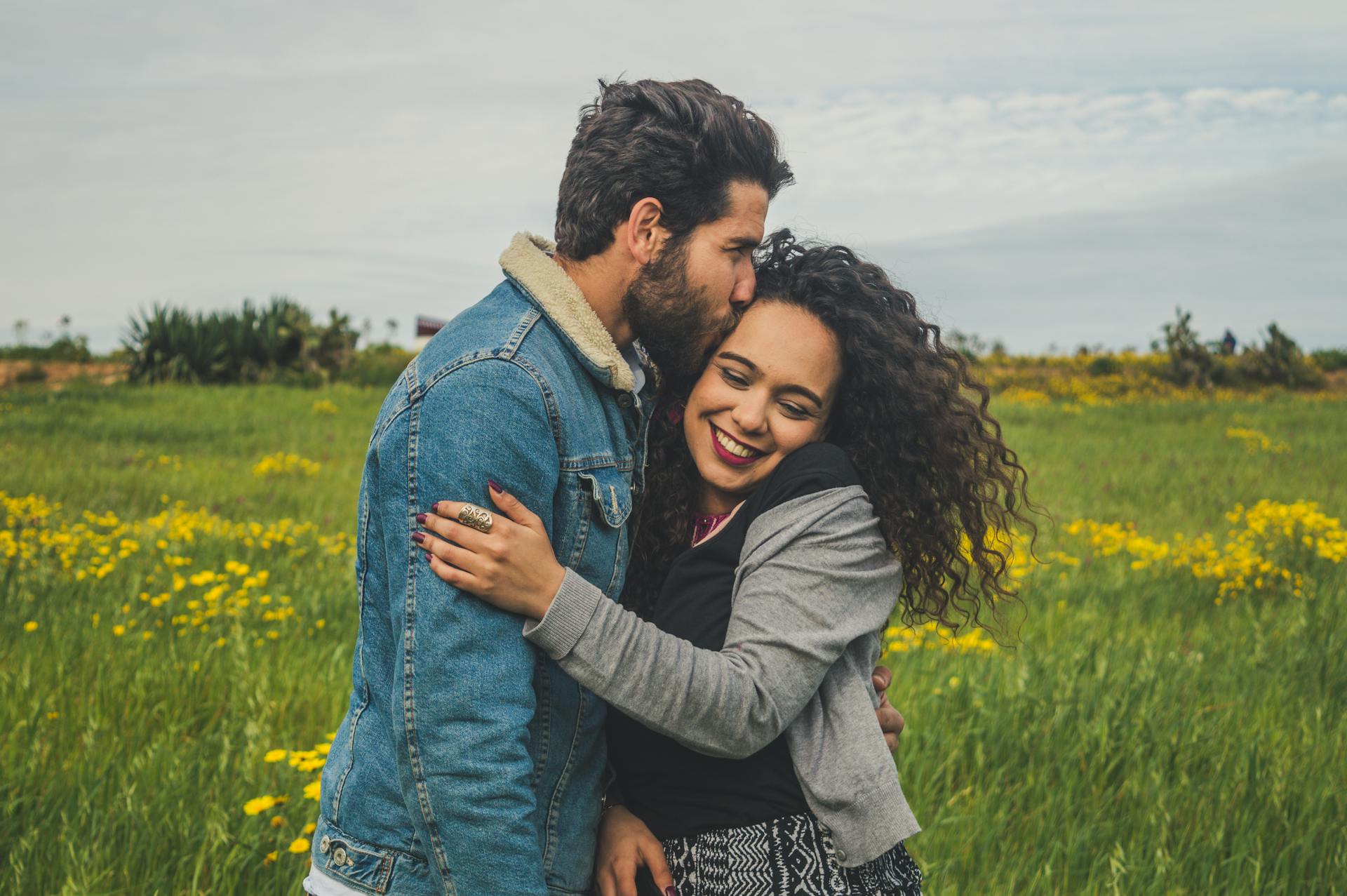 Ein junges Paar lächelt auf einem Feld | Quelle: Pexels