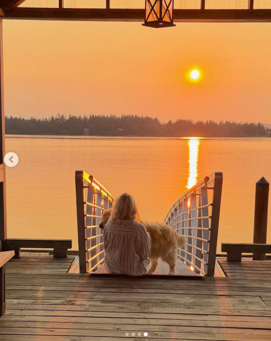 Pamela Anderson genießt den ruhigen Rhythmus des Küstenlebens in Arcady und sitzt neben einem ihrer Hunde auf einem Holzsteg, während in Ladysmith, British Columbia, ein strahlender Sonnenuntergang zu sehen ist. Von hinten gesehen, in einem übergroßen gestreiften Hemd, blickt sie über das leuchtende Wasser, während die Abendsonne hinter den Baumwipfeln versinkt, und teilt diesen ruhigen Moment mit ihren Followern zusammen mit dem Kommentar: „Im Herzen ein Inselmädchen 🤍.“ | Quelle: Instagram/pamelaanderson