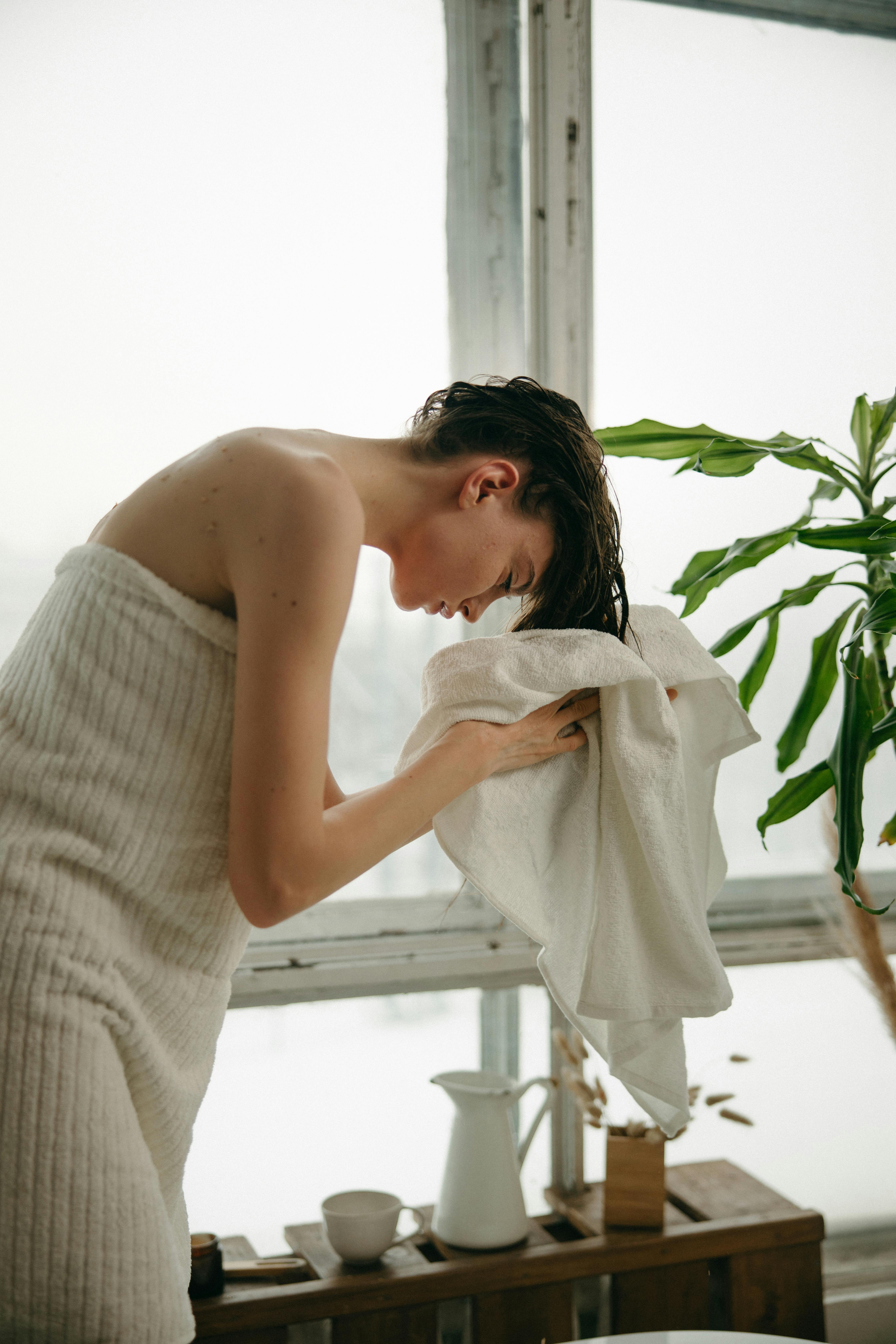 Uma mulher seca o cabelo com uma toalha após o banho | Fonte: Pexels