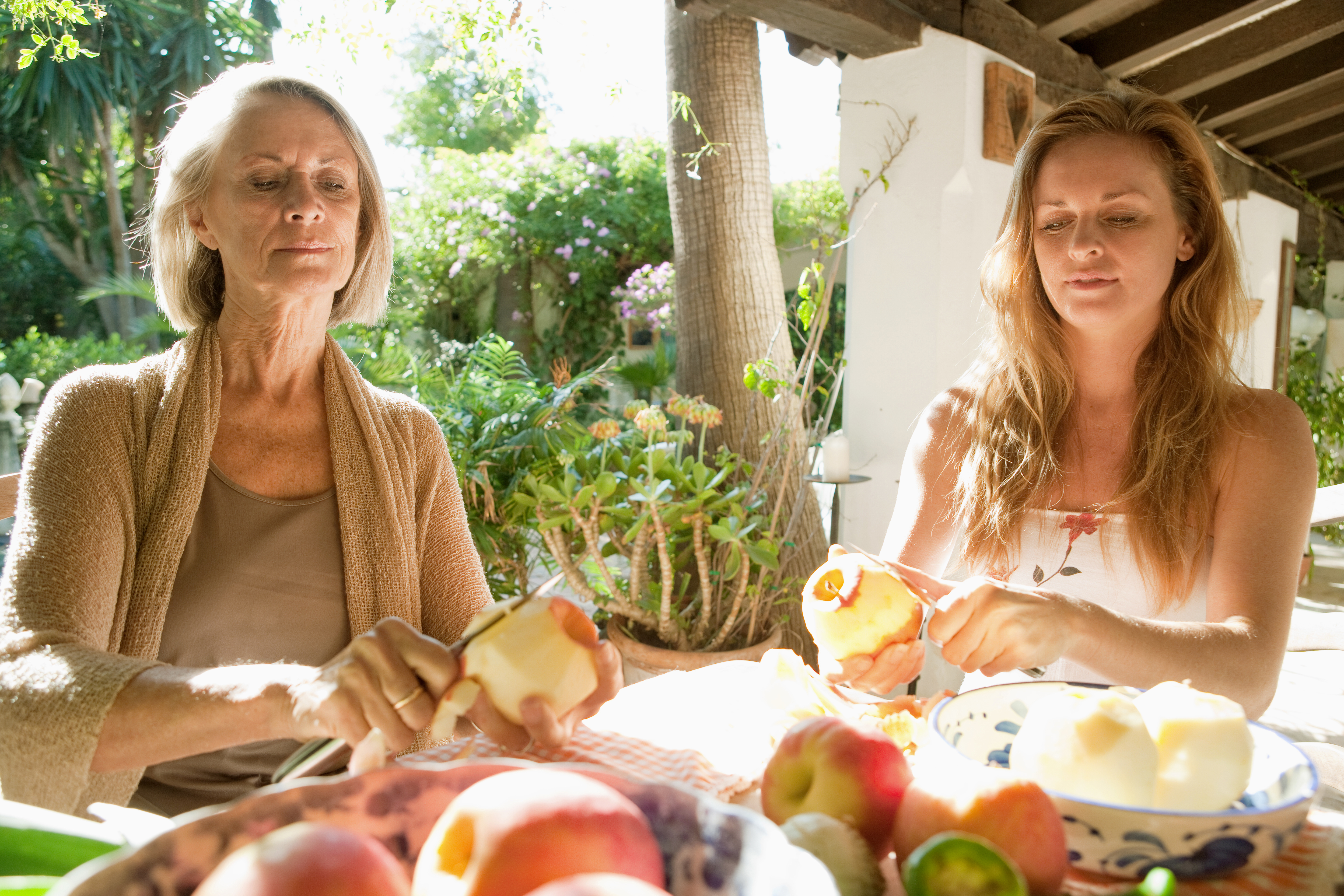 Zwei Frauen an einem Esstisch, die Äpfel schälen | Quelle: Shutterstock