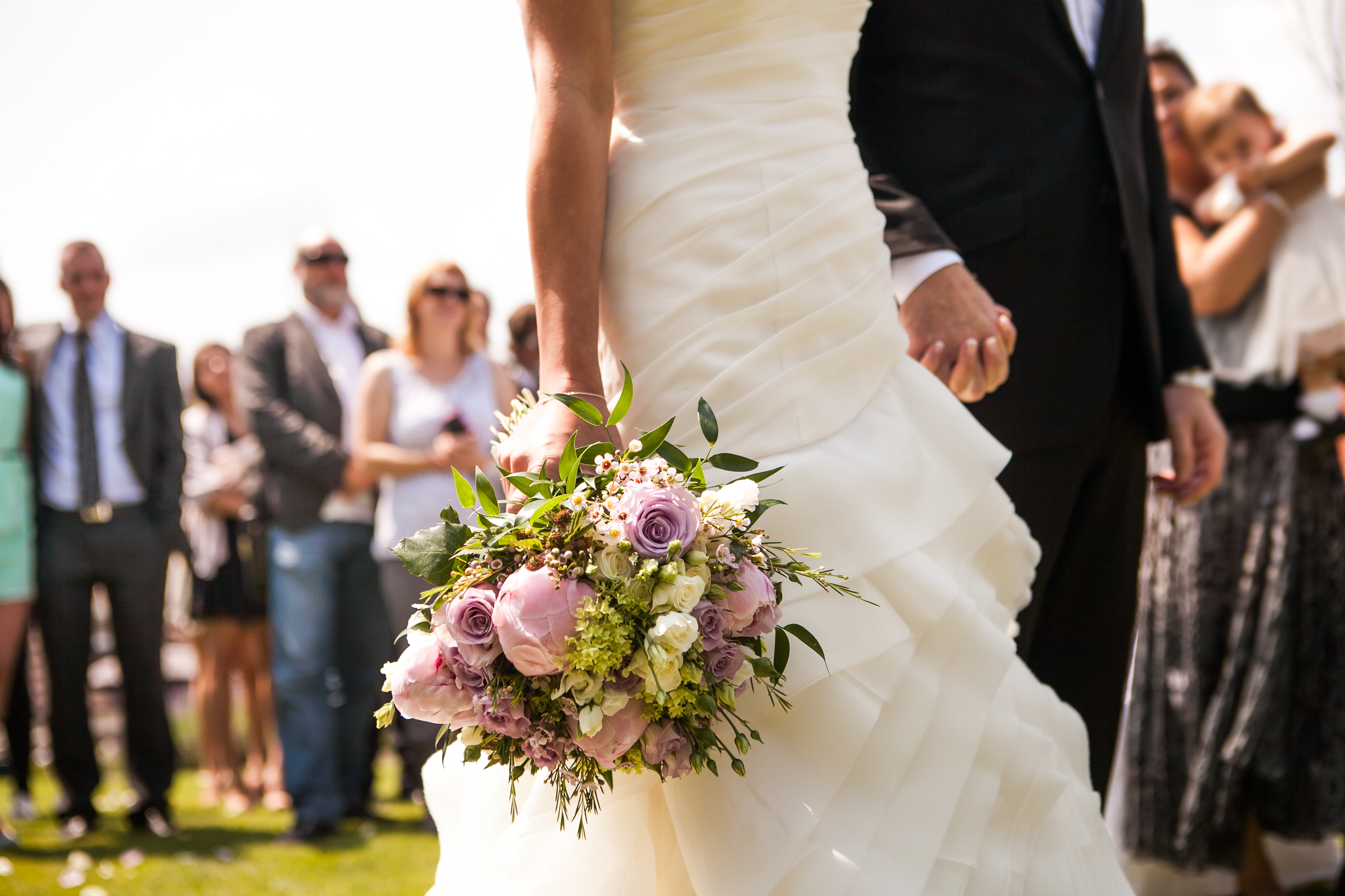 Eine Braut und ein Bräutigam halten sich bei ihrer Hochzeit an den Händen | Quelle: Shutterstock