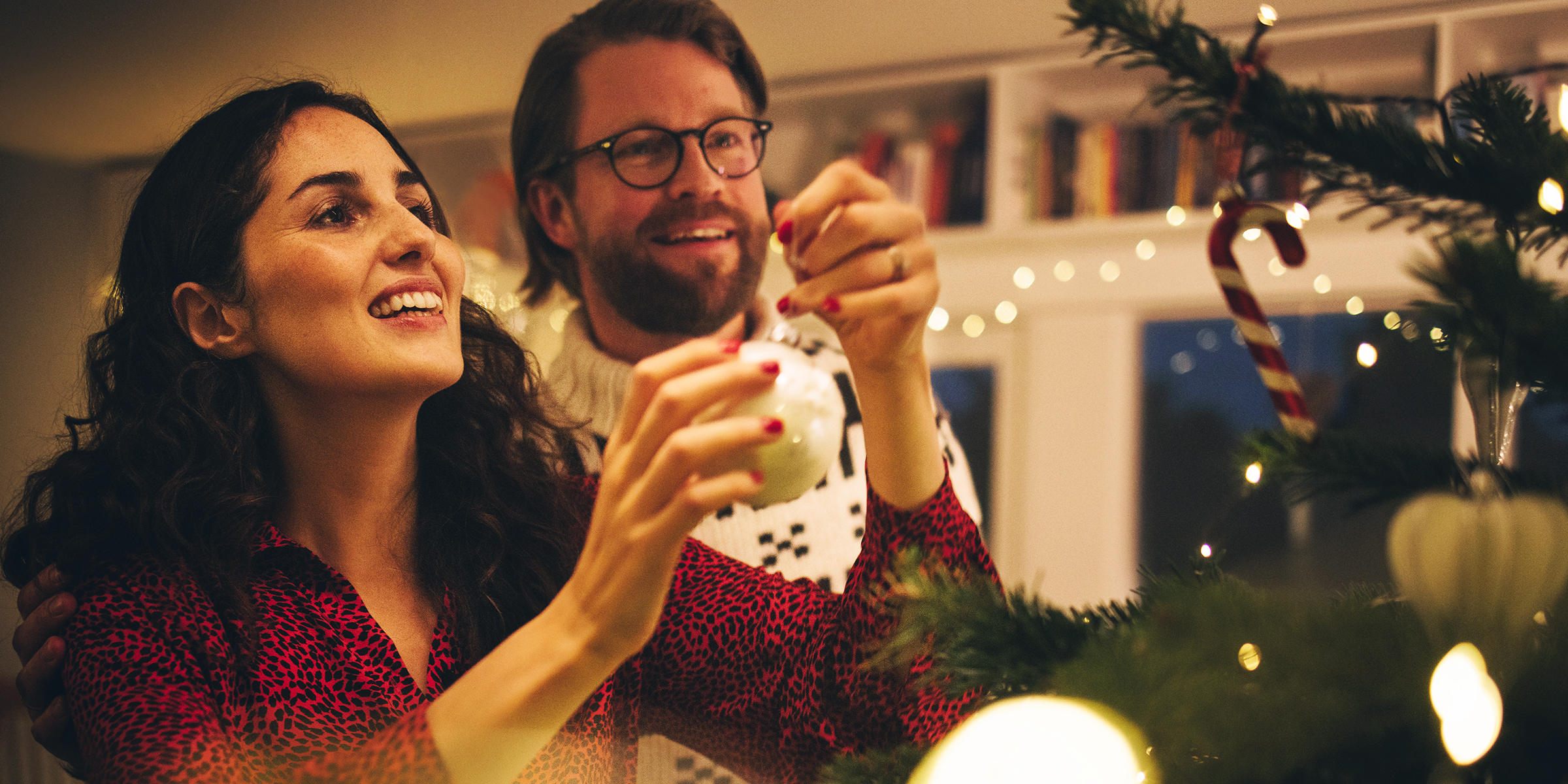 Ein Paar schmückt einen Weihnachtsbaum | Quelle: Shutterstock