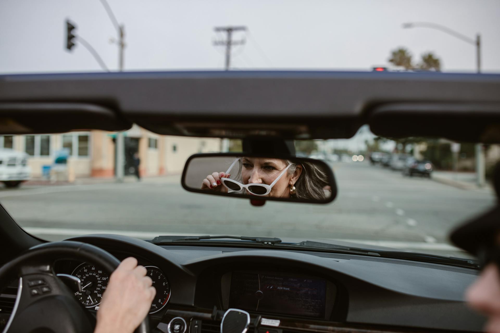 Die Reflexion einer Frau mittleren Alters im Rückspiegel beim Autofahren | Quelle: Pexels