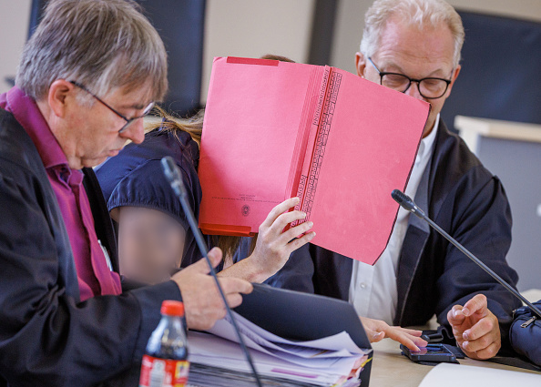 Die Angeklagte sitzt zwischen ihren Anwälten Andreas Ohm (l.) und Thomas Löcker (r.) im Gerichtssaal des Landgerichts Rostock, 1. Juli 2026. | Quelle: Getty Images