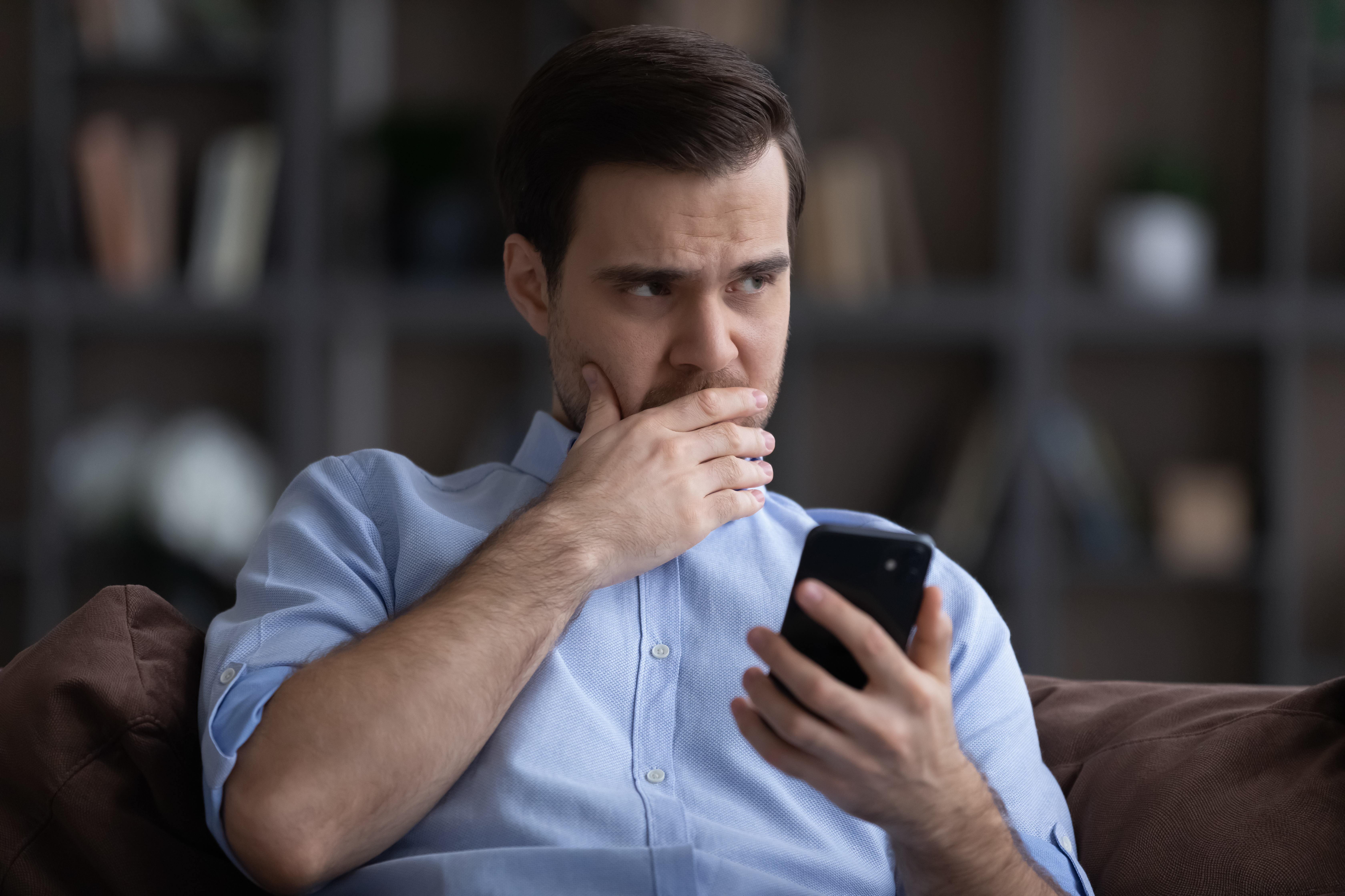 Besorgter Mann, der an etwas zweifelt, während er sein Telefon hält | Quelle: Shutterstock