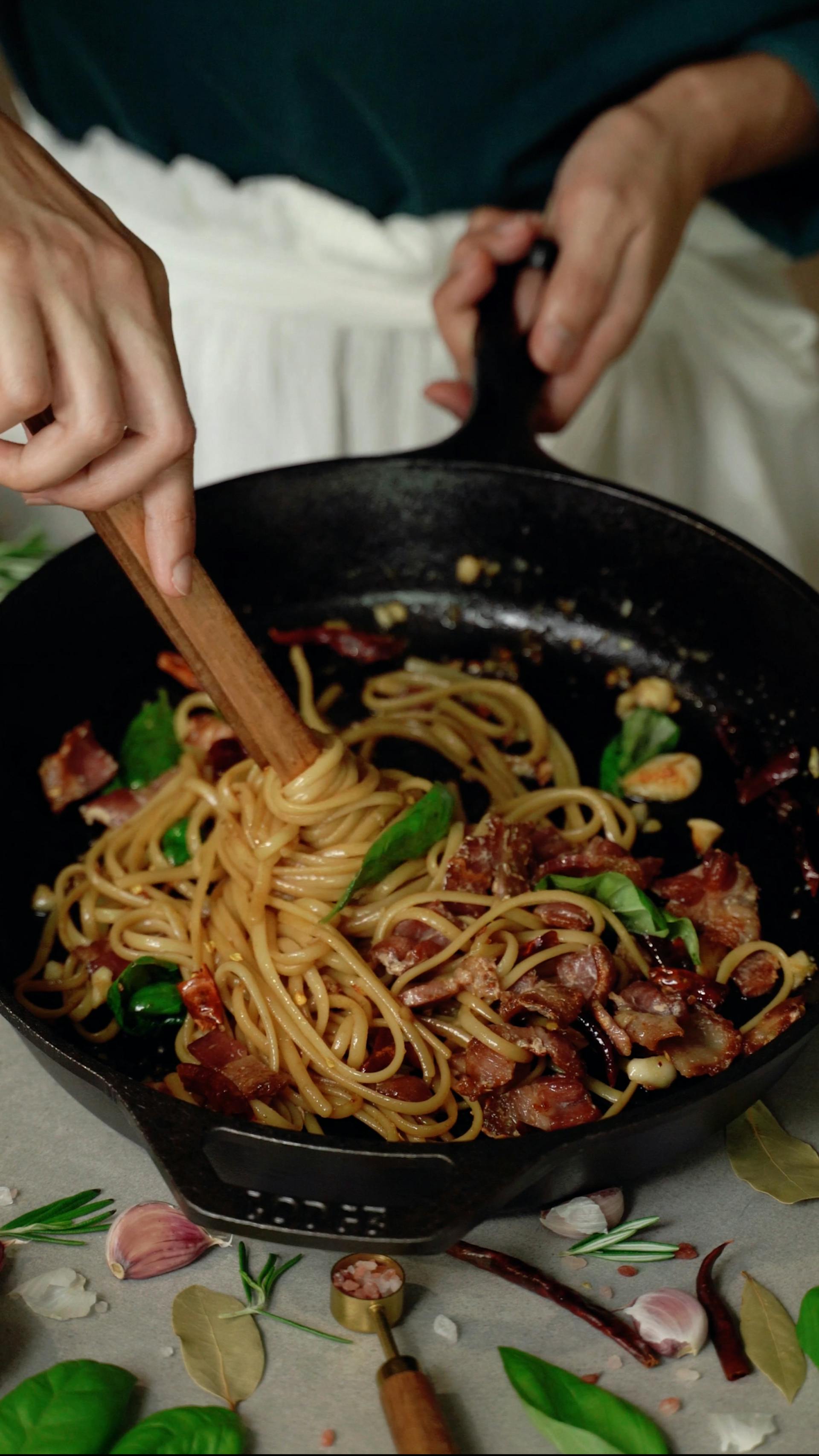 Eine Nahaufnahme einer Frau, die Spaghetti in einer Pfanne schwenkt | Quelle: Pexels