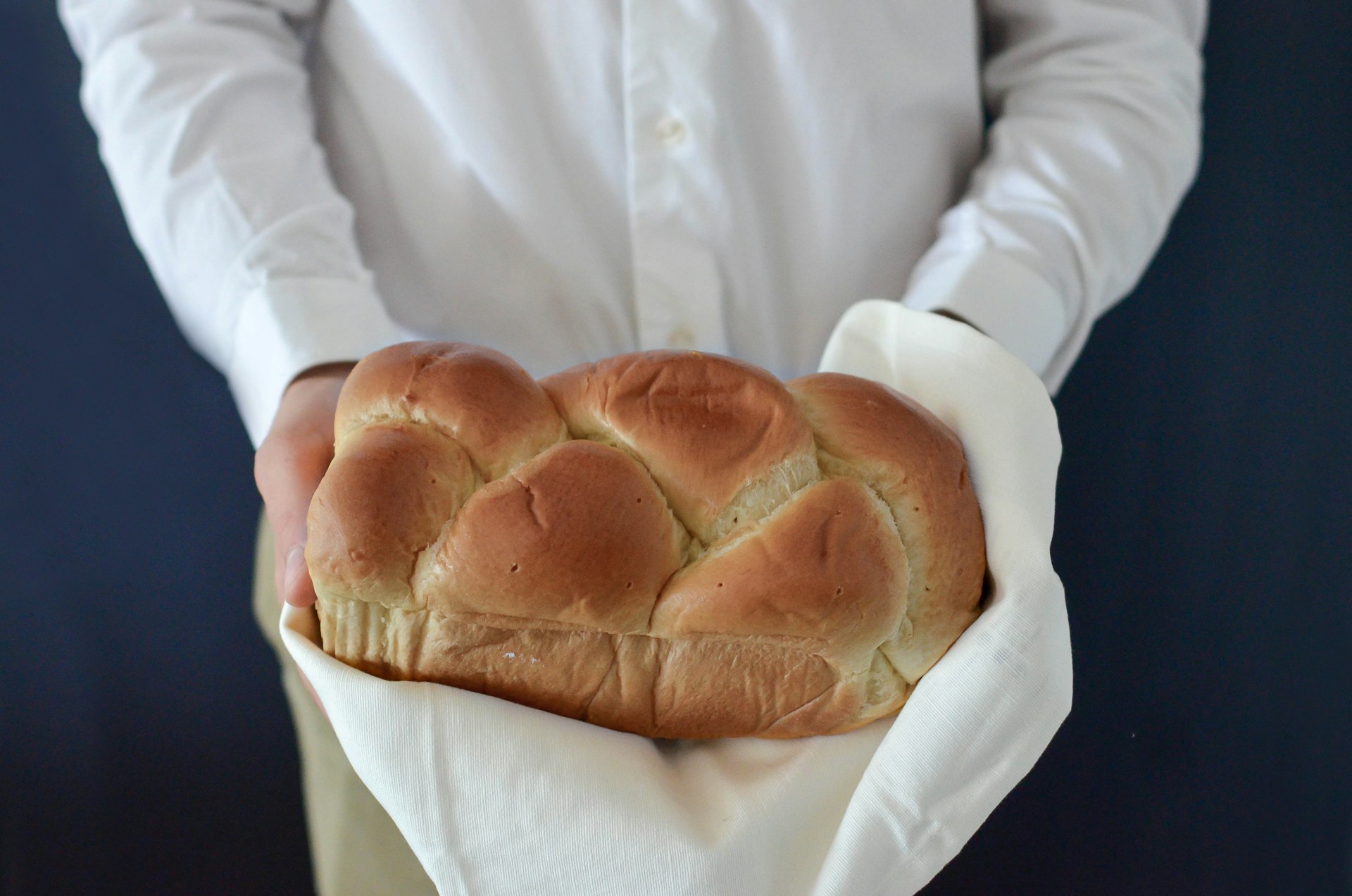 Nahaufnahme einer Frau mit frisch gebackenem Brot in der Hand | Quelle: Unsplash