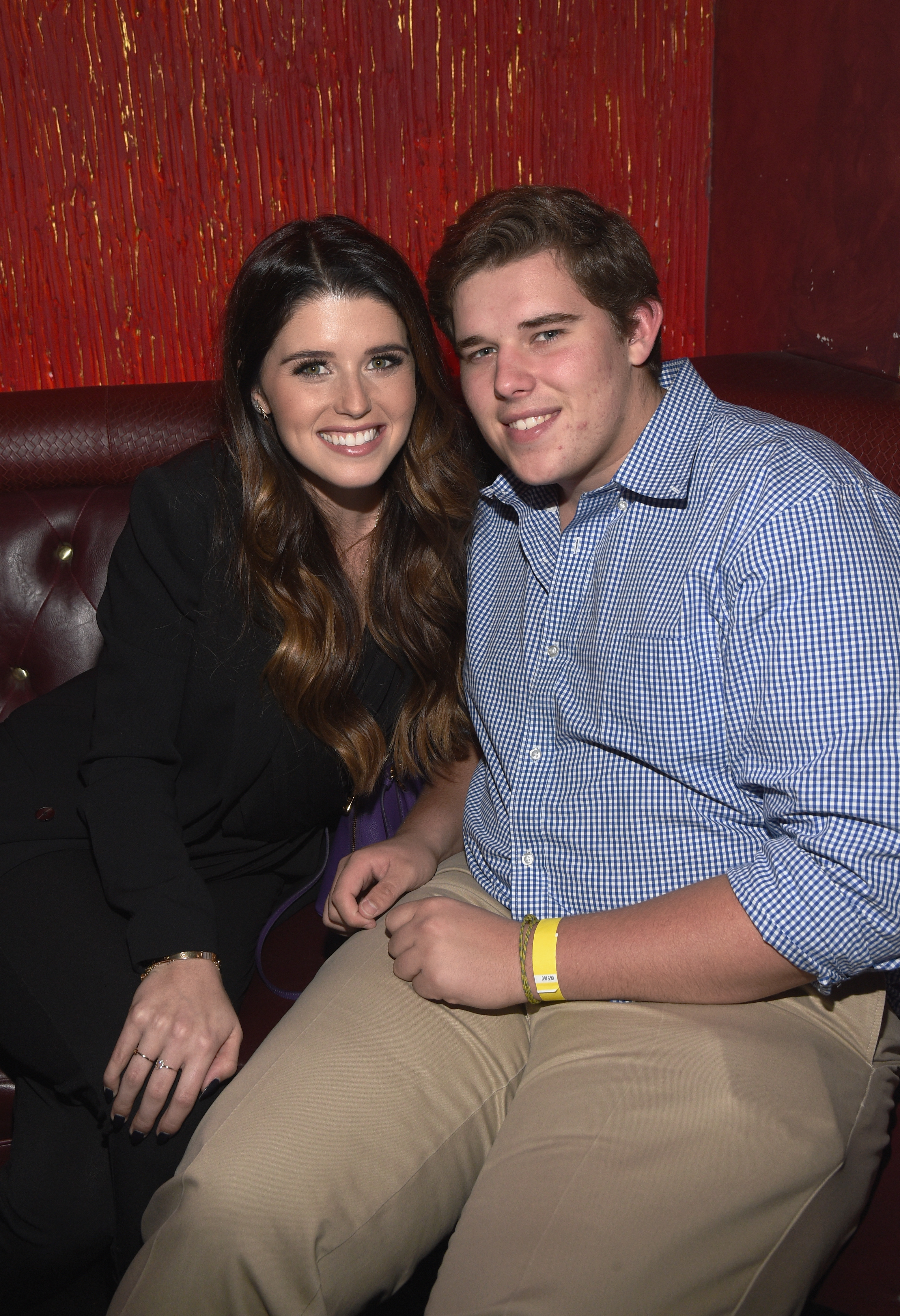Christopher sitzt neben seiner Schwester Katherine beim Vorempfang einer Veranstaltung in Los Angeles, im Dezember 2014. Er trägt ein blau-kariertes Hemd und eine beigefarbene Hose, an seinem rechten Handgelenk ist ein gelbes Armband zu sehen. Sein runderes Gesicht und sein entspanntes Auftreten spiegeln seinen Stil in dieser Zeit wider.