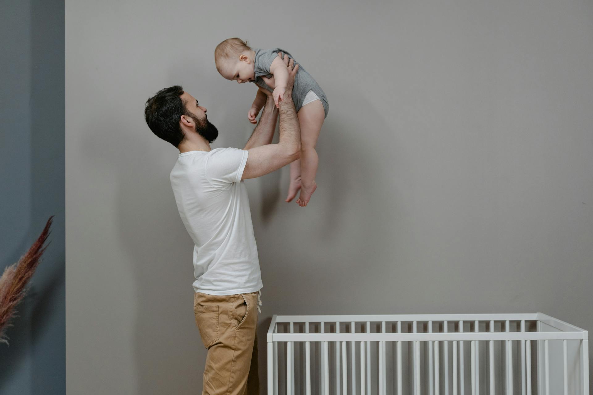 Ein Mann, der ein Baby aus einem Kinderbettchen hebt | Quelle: Pexels