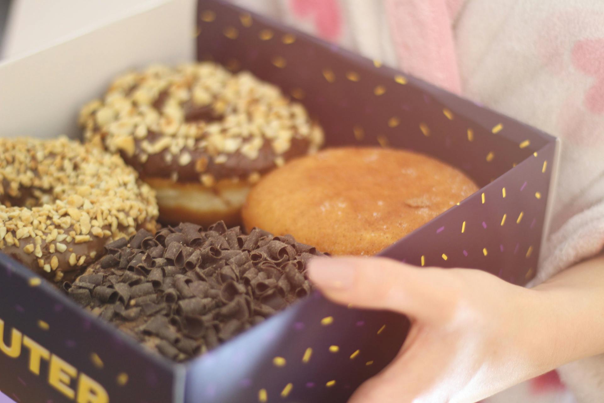 Eine Frau hält eine Schachtel mit Donuts | Quelle: Pexels