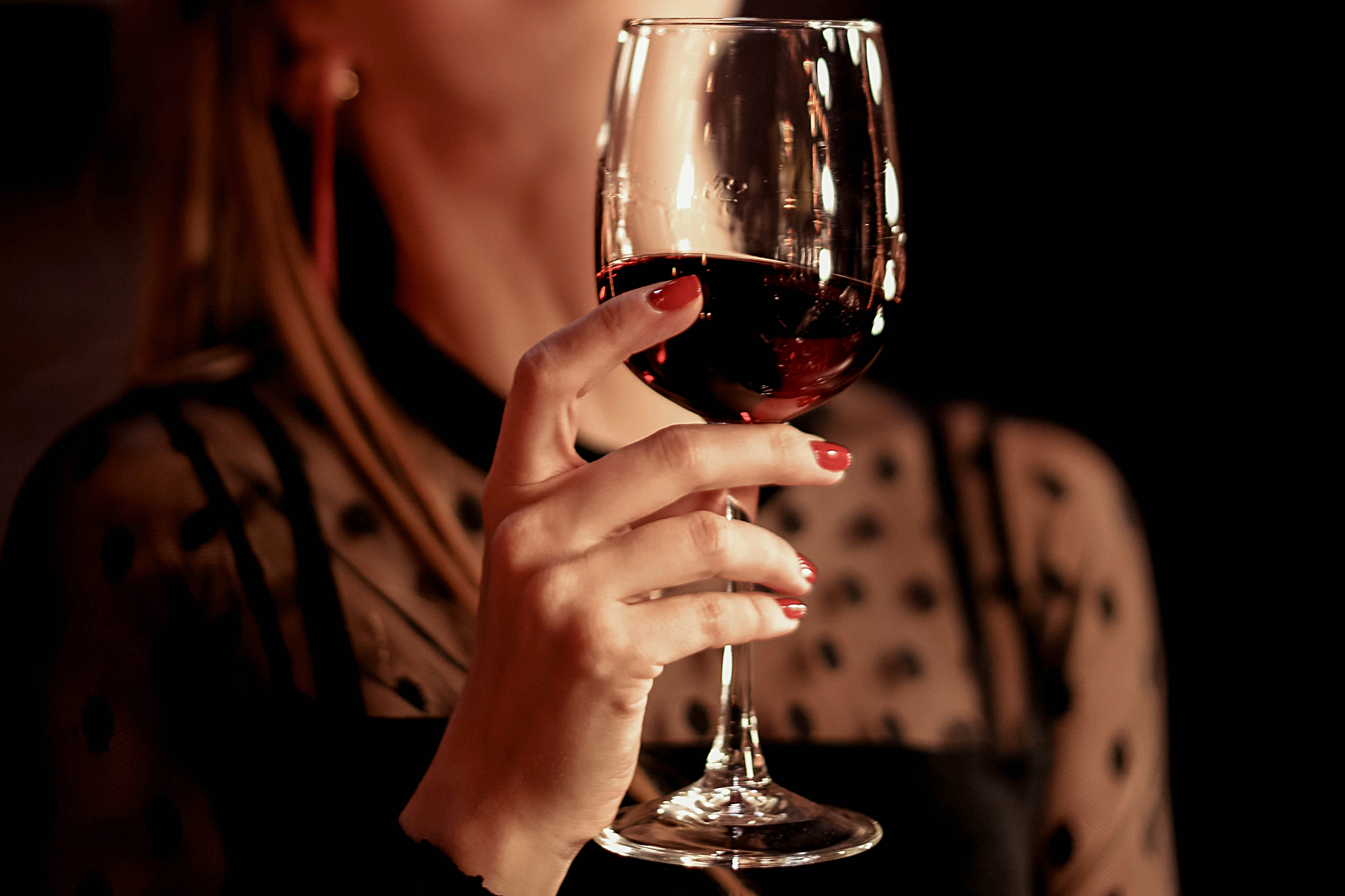 Weibliche Hand hält ein Glas Rotwein | Quelle: Shutterstock