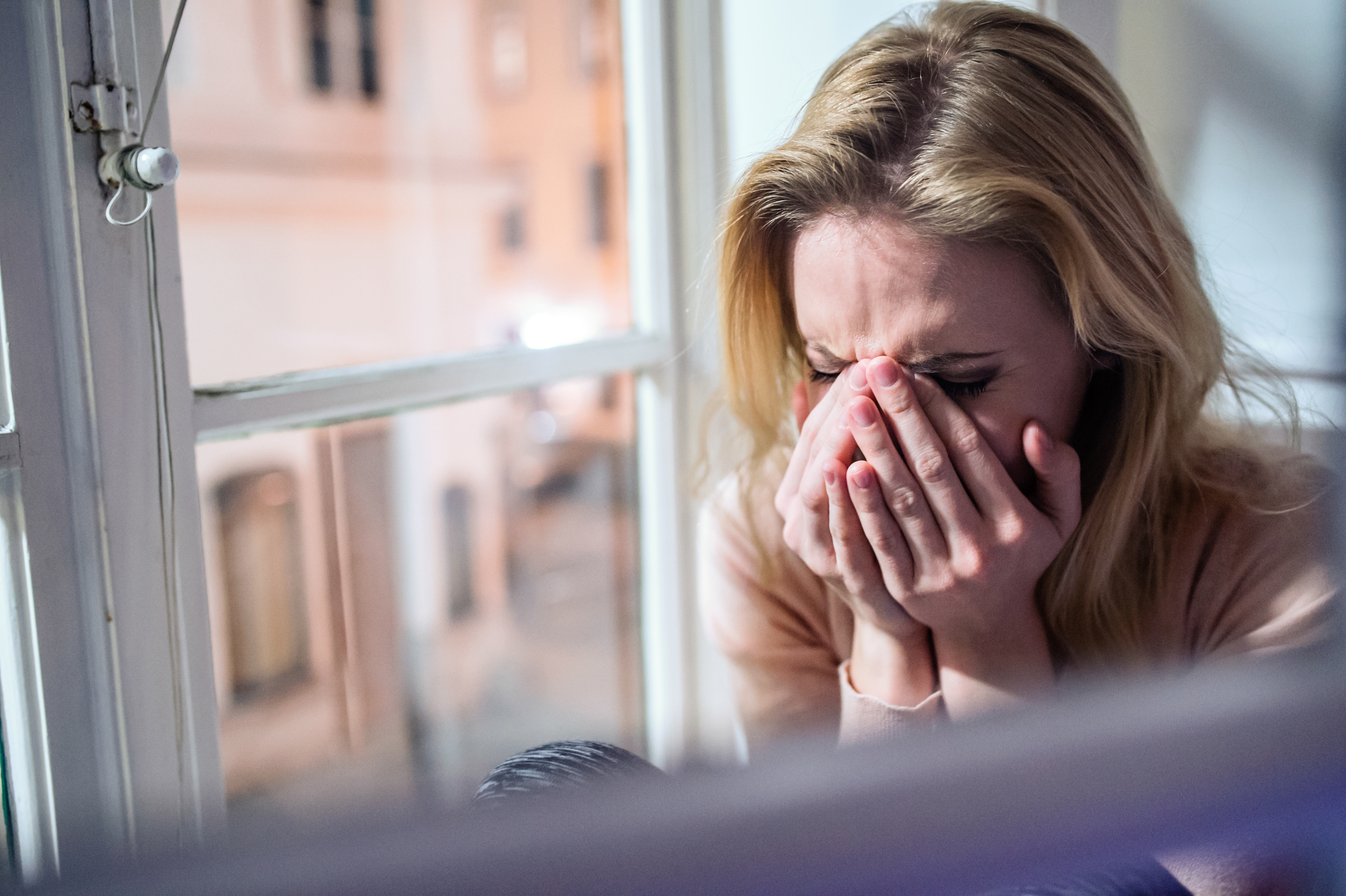 Eine weinende Frau, die neben dem Fenster sitzt | Quelle: Shutterstock