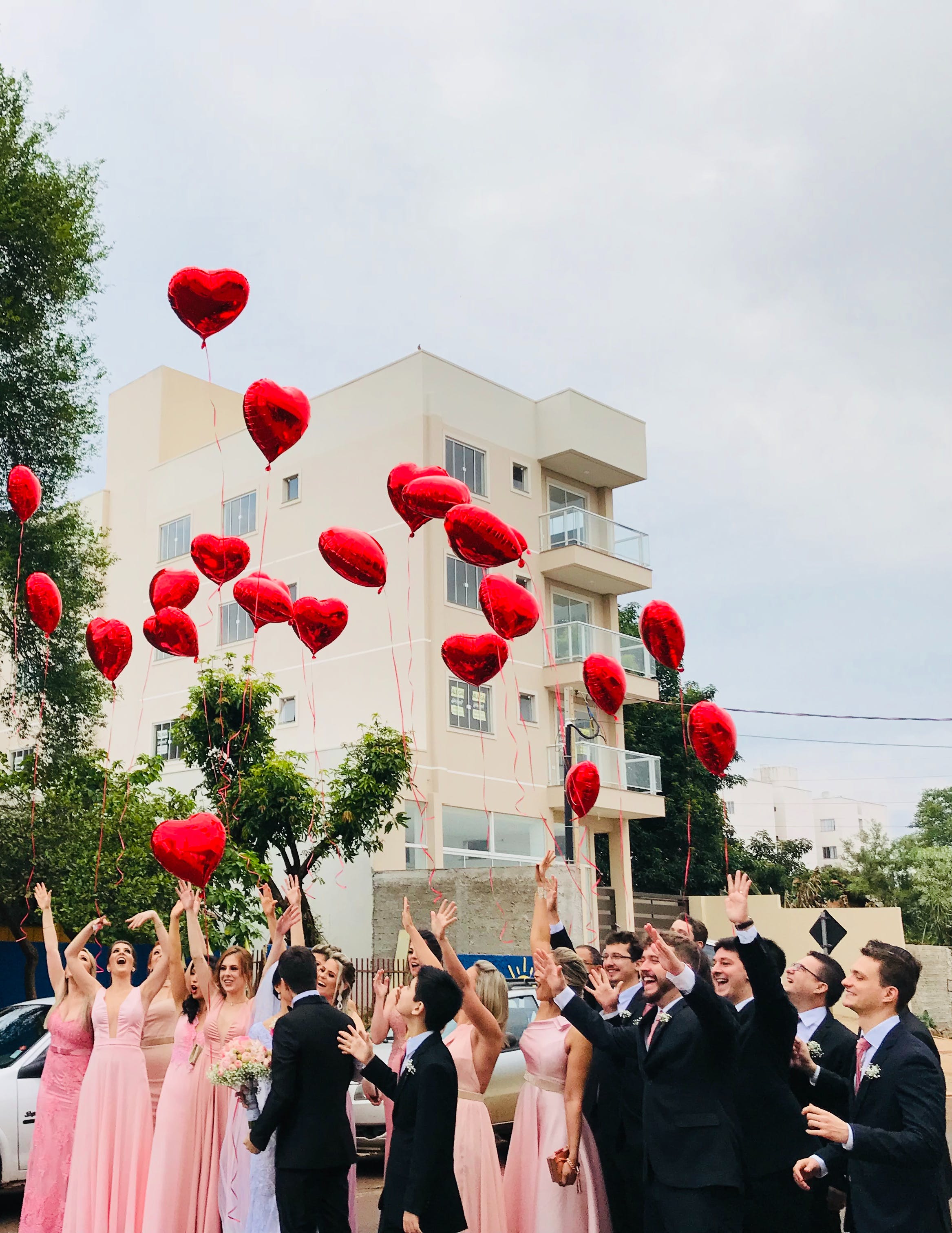 Eine Hochzeitsgesellschaft lässt herzförmige Luftballons auf der Straße steigen | Quelle: Pexels