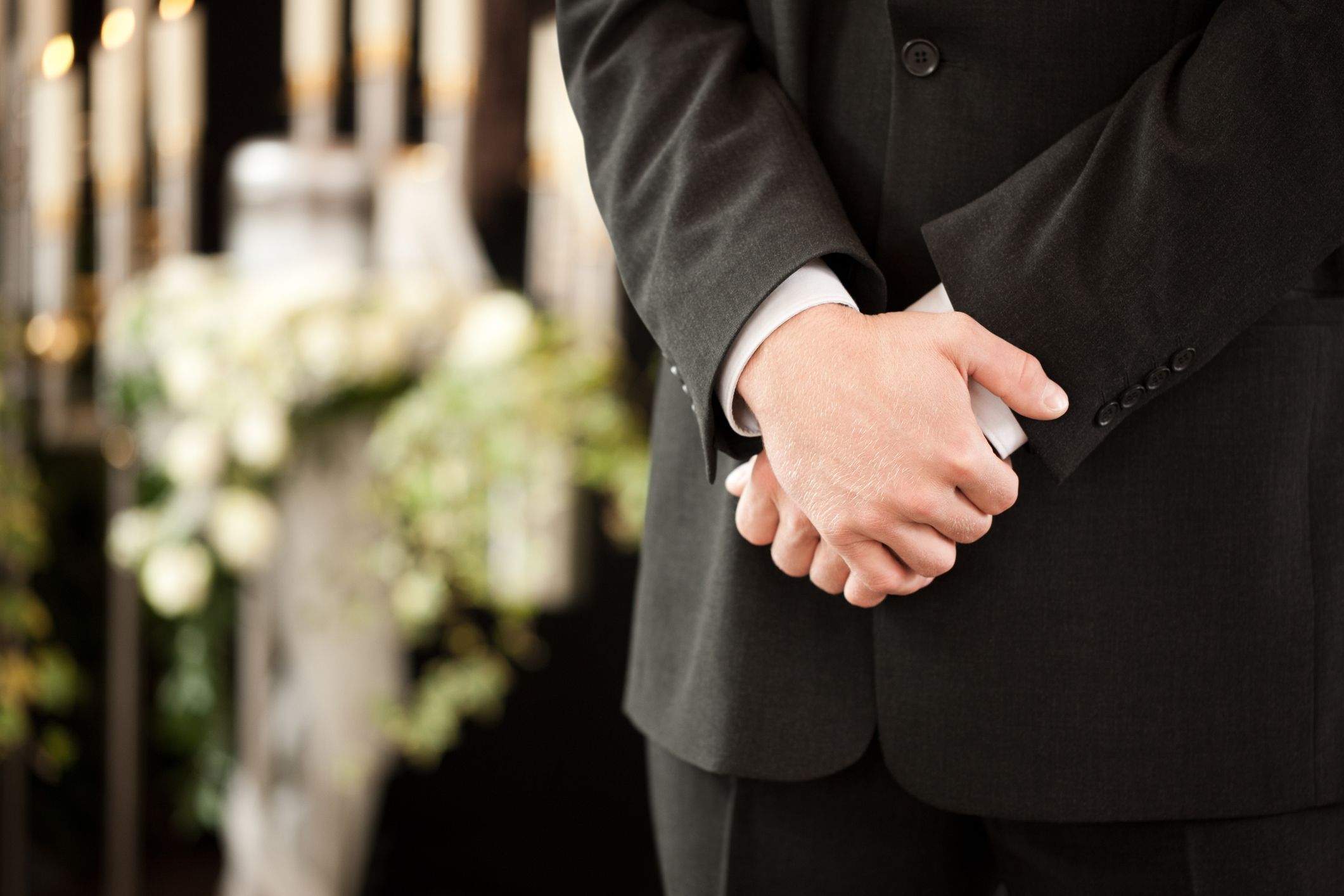 Ein Mann bei einer Beerdigung hält seine Hände über einander. | Quelle: Getty Images
