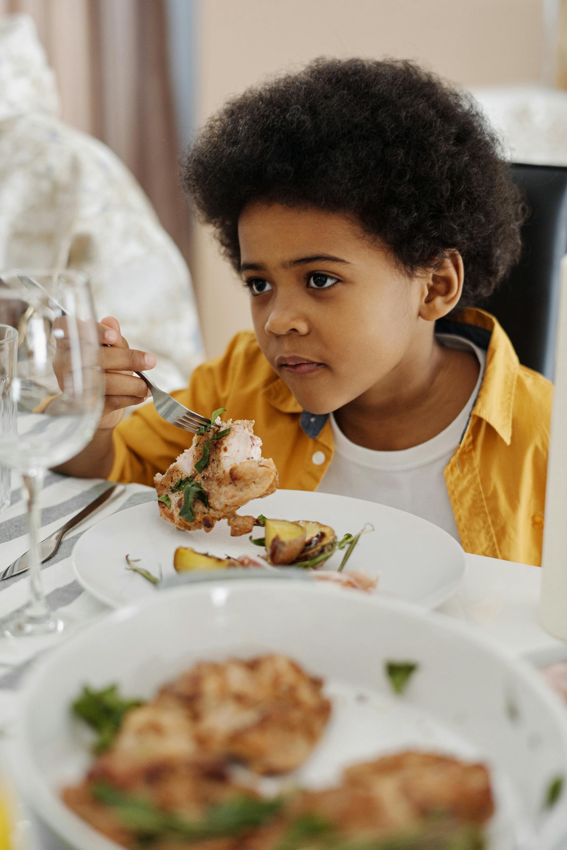 Verwirrt dreinschauender Junge beim Abendessen | Quelle: Pexels