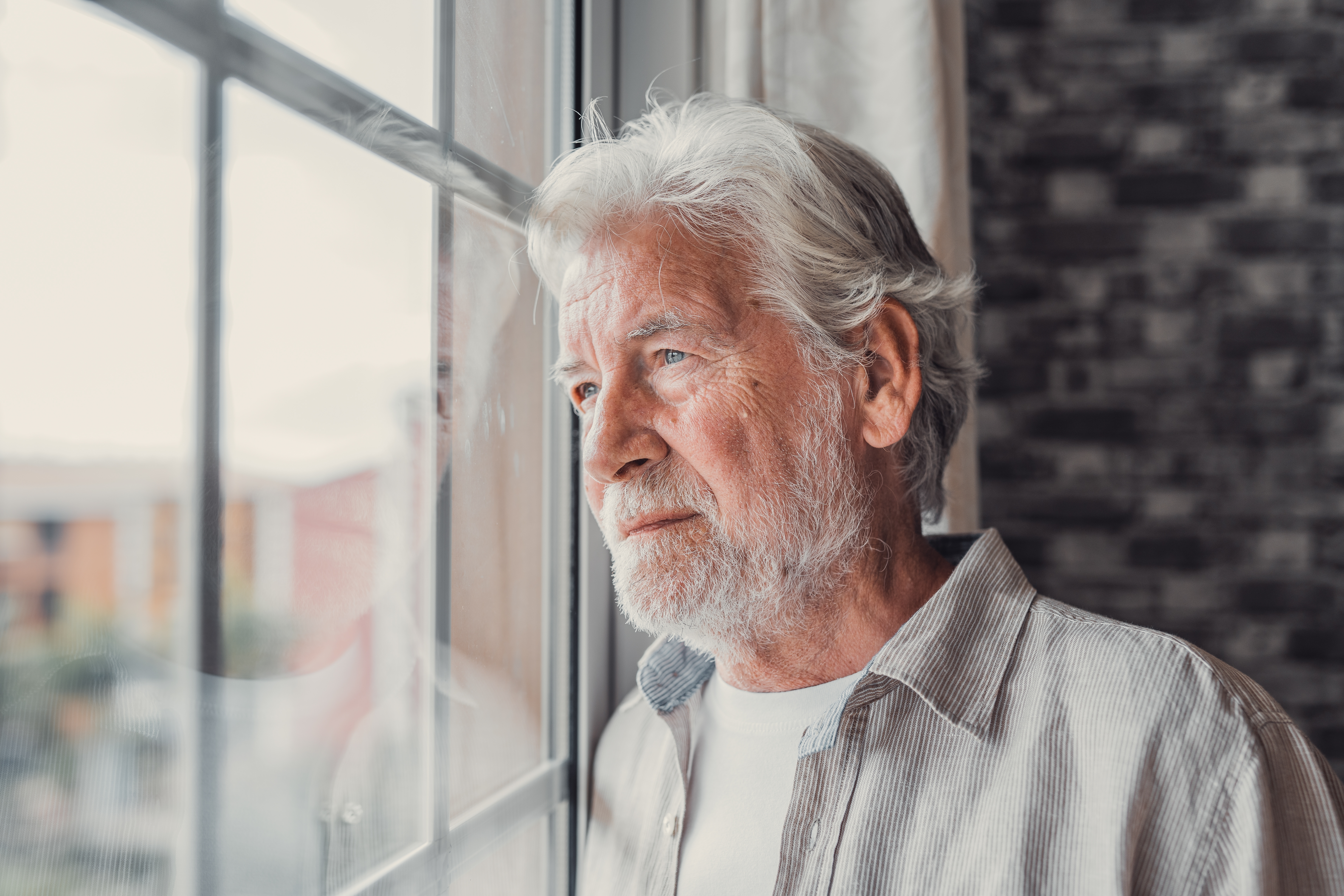Ein nachdenklicher älterer Mann, der aus dem Fenster schaut | Quelle: Shutterstock