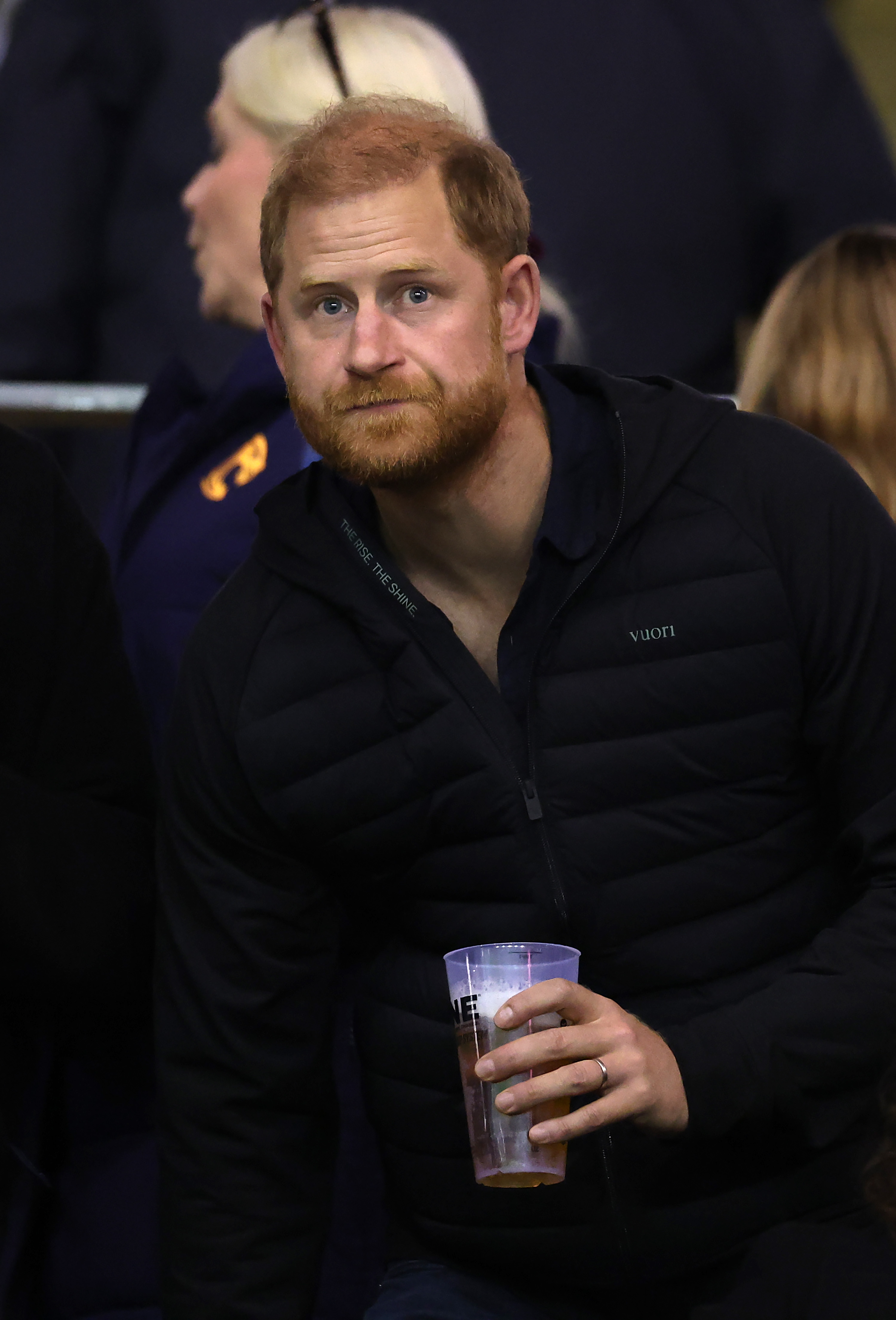 Prinz Harry hält einen Plastikbecher in der Hand, während er das Spiel von der Tribüne im Welford Road Stadium in Leicester aus verfolgt – diese Momente wurden während seines Ausflugs am 9. Oktober 2026 festgehalten. | Quelle: Getty Images