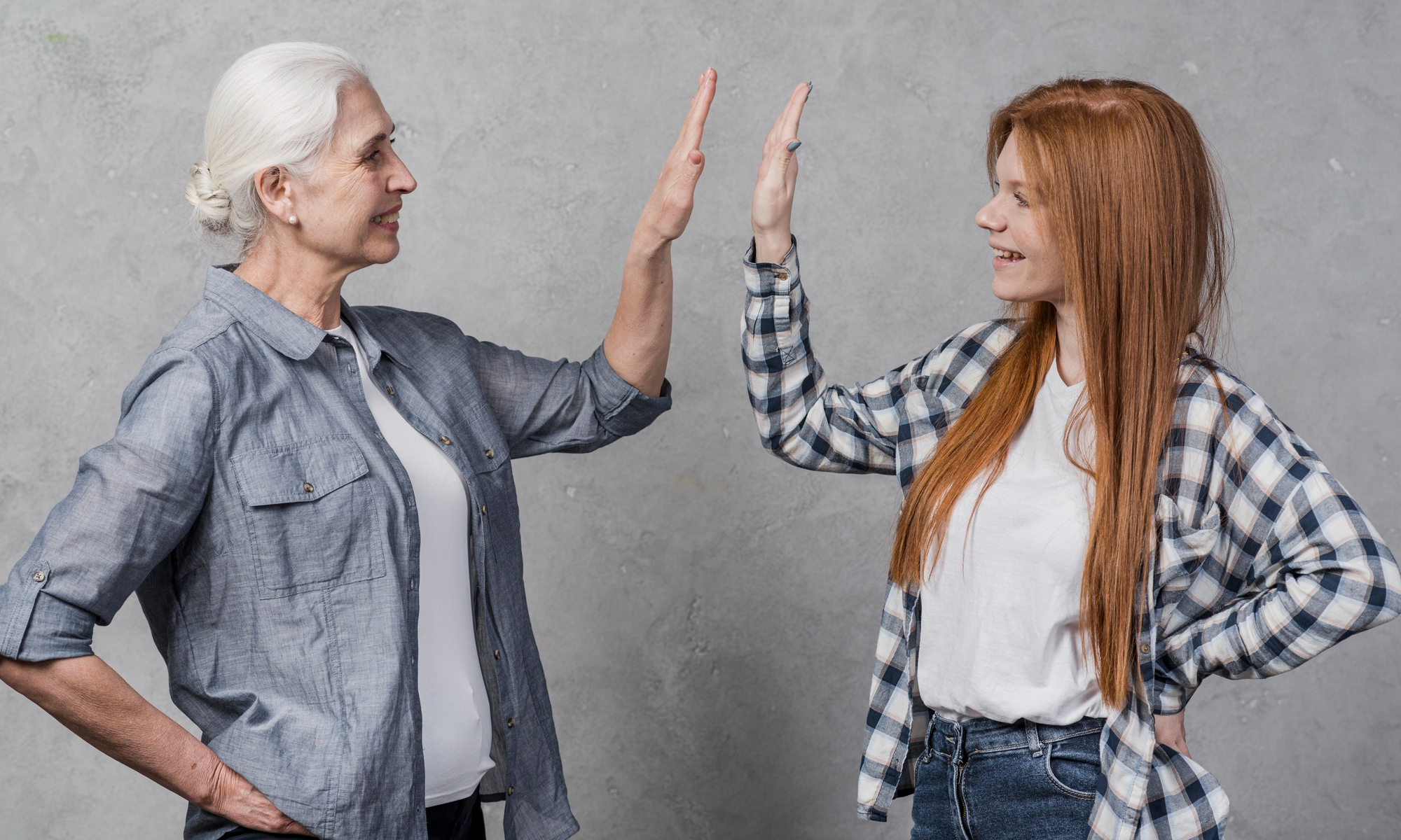 Eine ältere Frau und eine junge Frau geben sich ein High Five | Quelle: Freepik