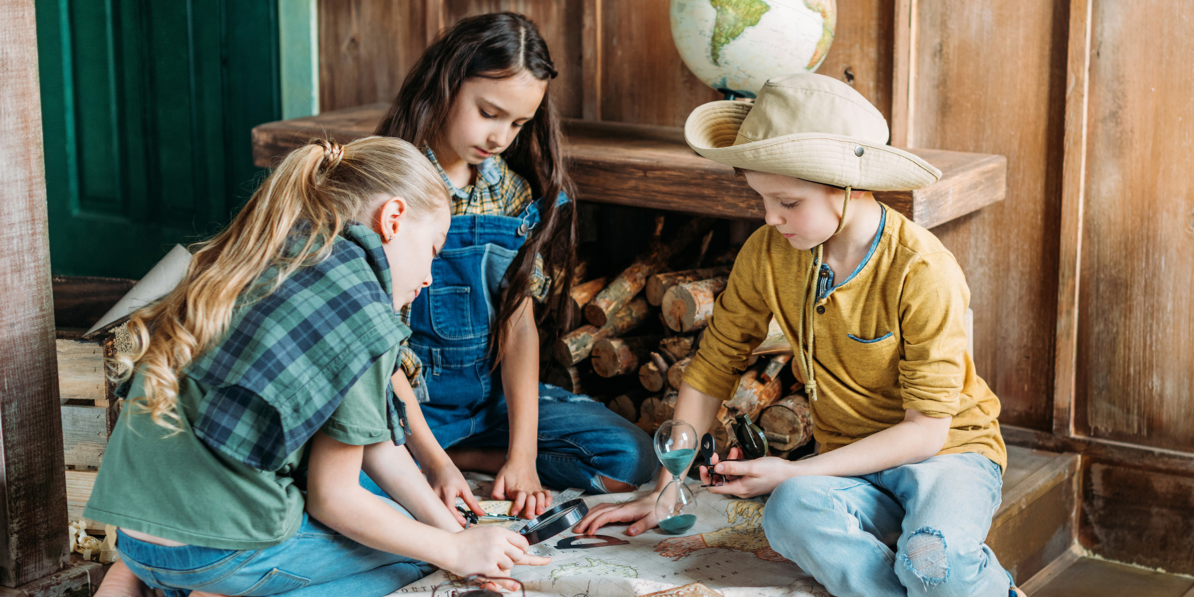 Drei Kinder spielen mit einer Karte | Quelle: Shutterstock