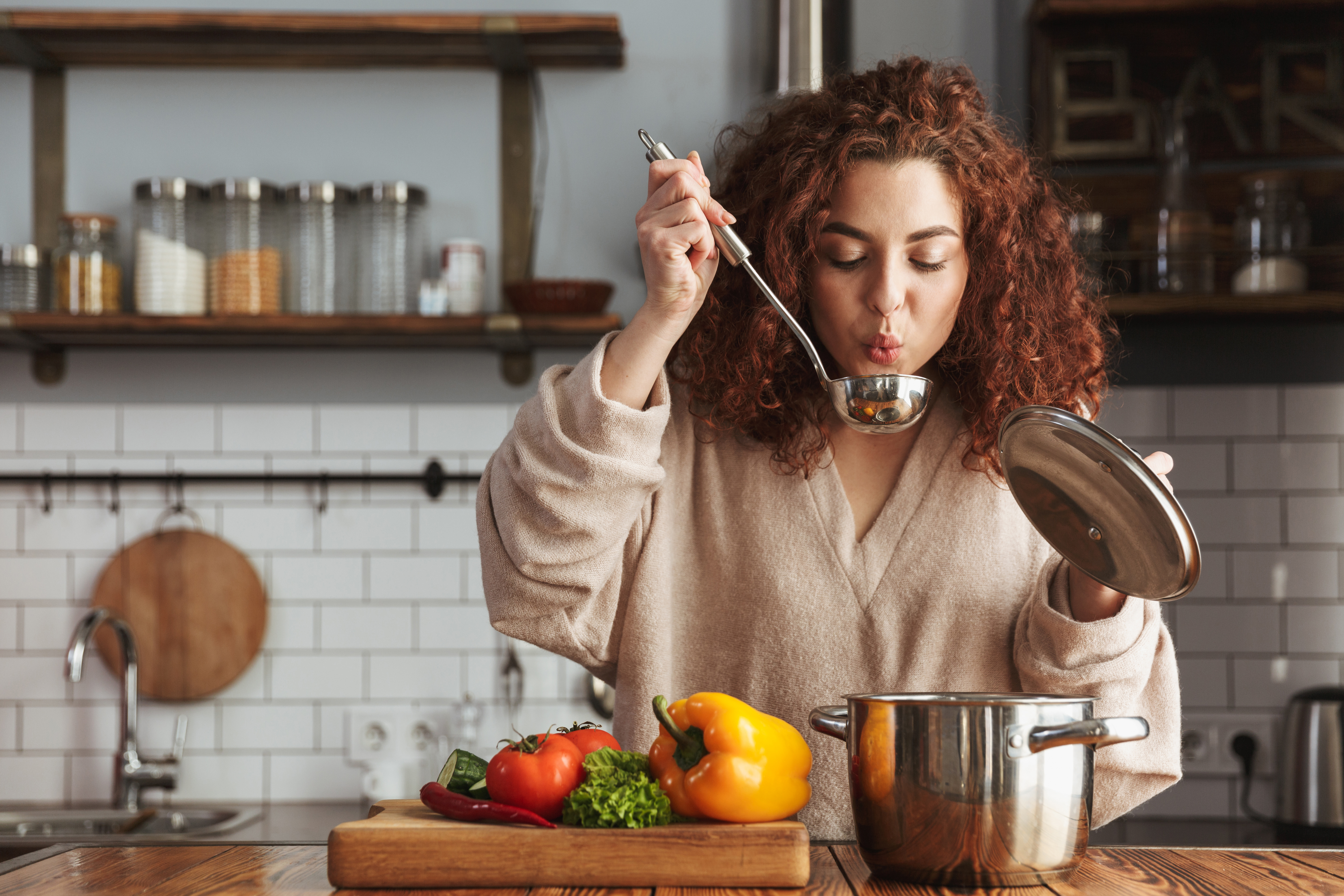 Eine Frau probiert das Essen, das sie gekocht hat | Quelle: Shutterstock