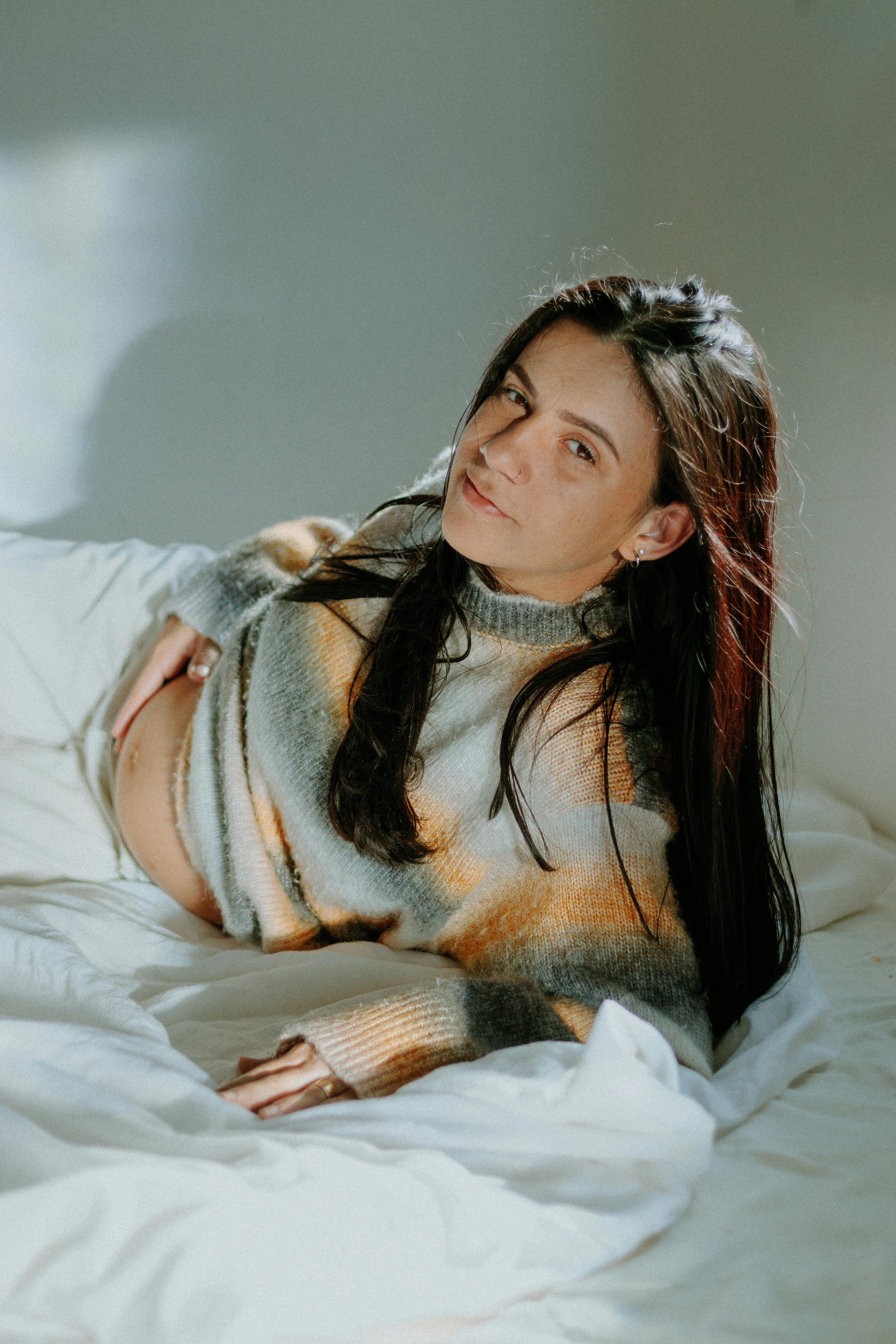 Eine schwangere Frau, die unzufrieden auf einem Bett liegt | Quelle: Pexels