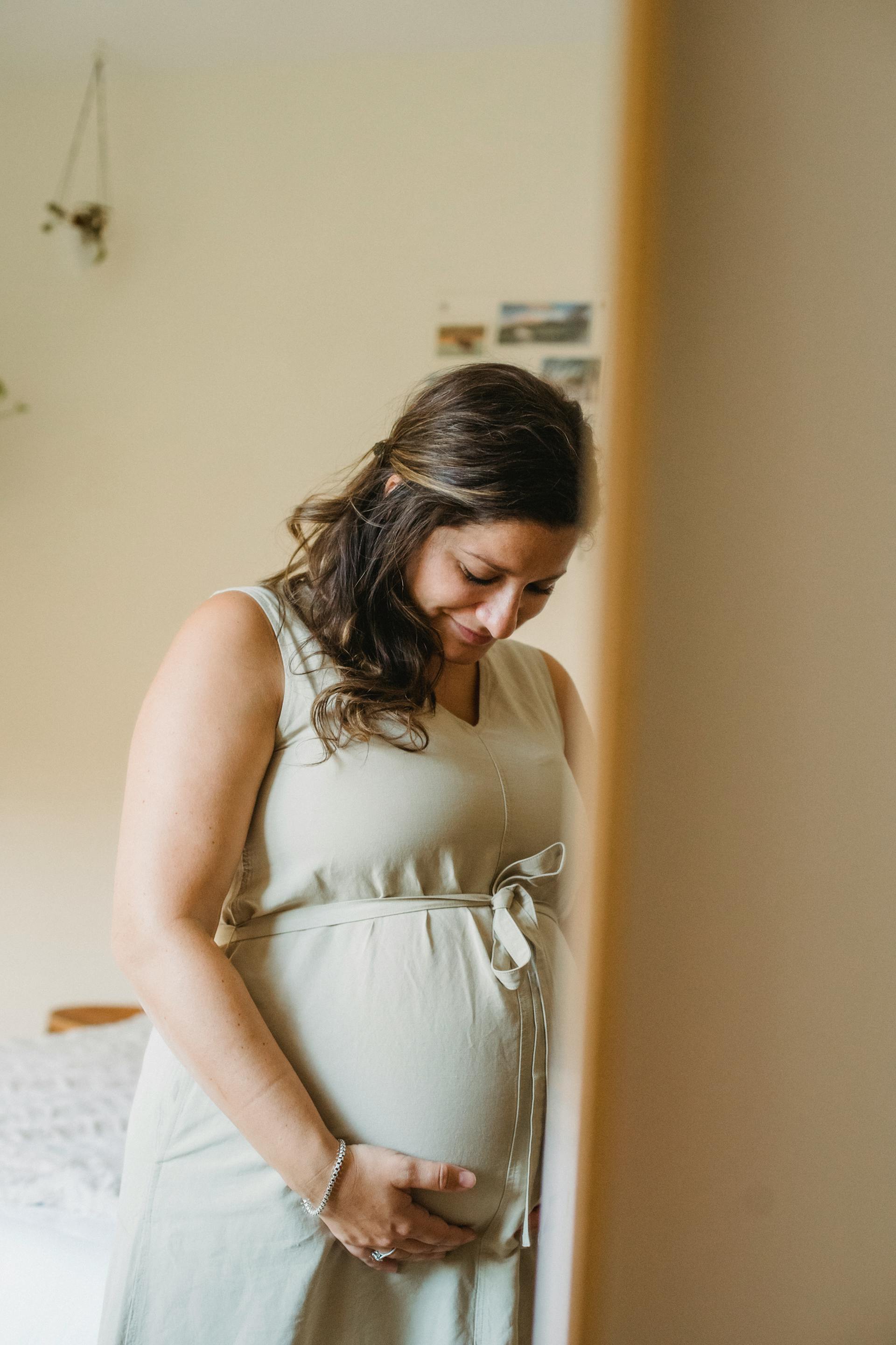 Eine Frau, die auf ihren schwangeren Bauch herunterlächelt | Quelle: Pexels