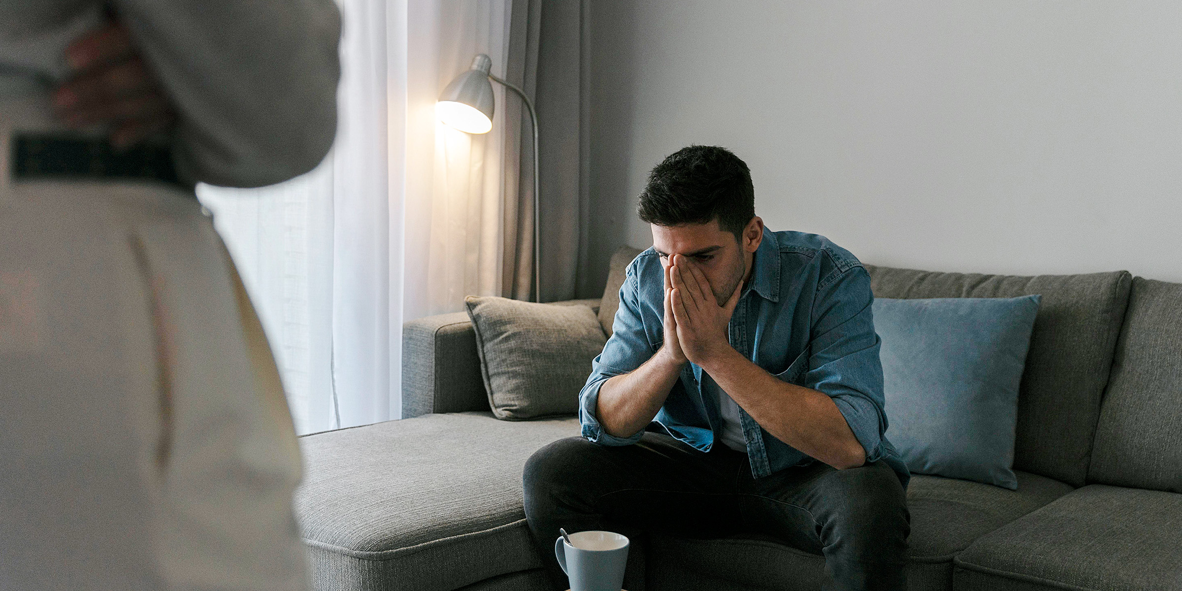 Ein Mann sitzt auf einer Couch und hält sich die Hände vors Gesicht | Quelle: Freepik