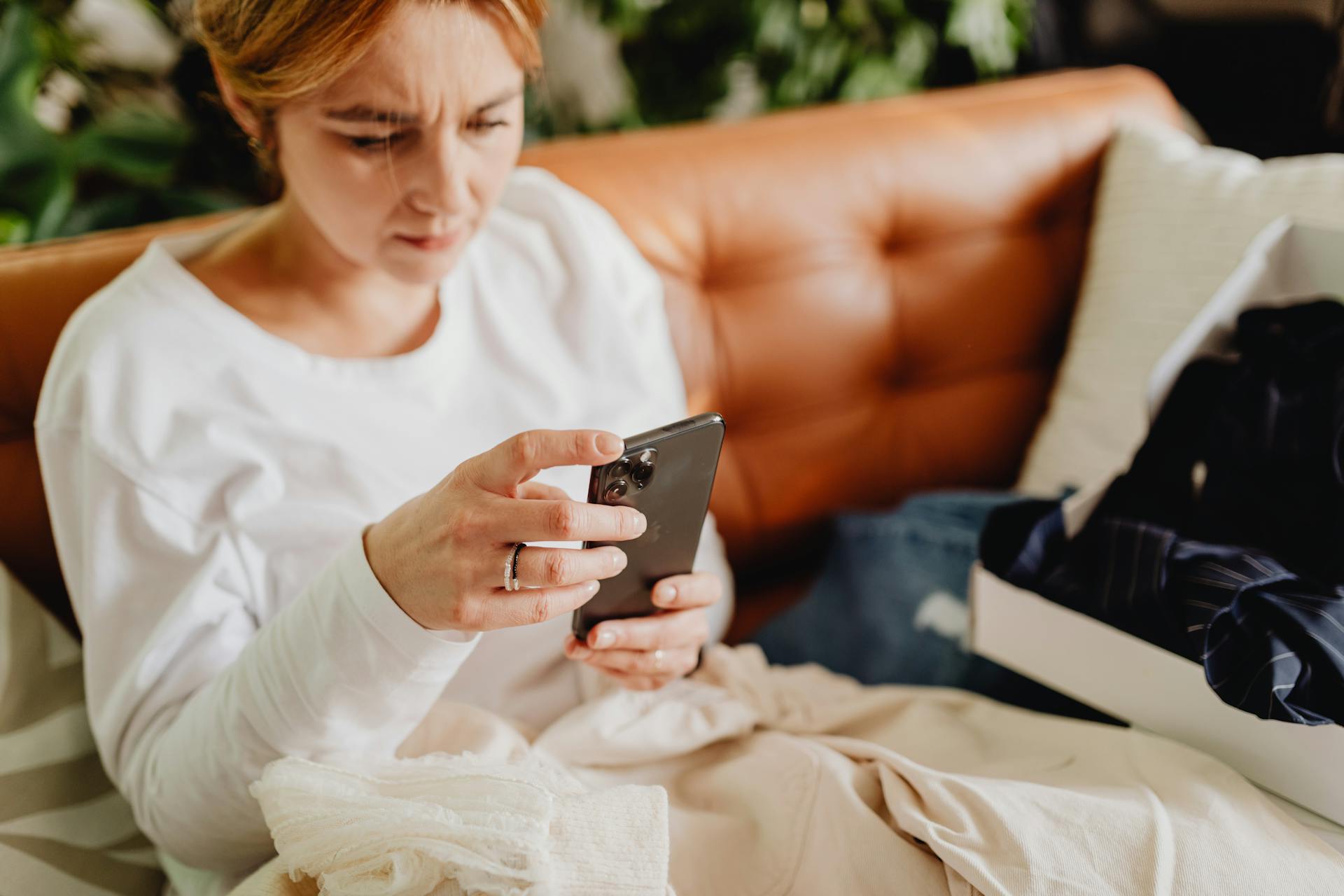 Eine Frau, die auf der Couch sitzt und ihr Smartphone in der Hand hält | Quelle: Pexels