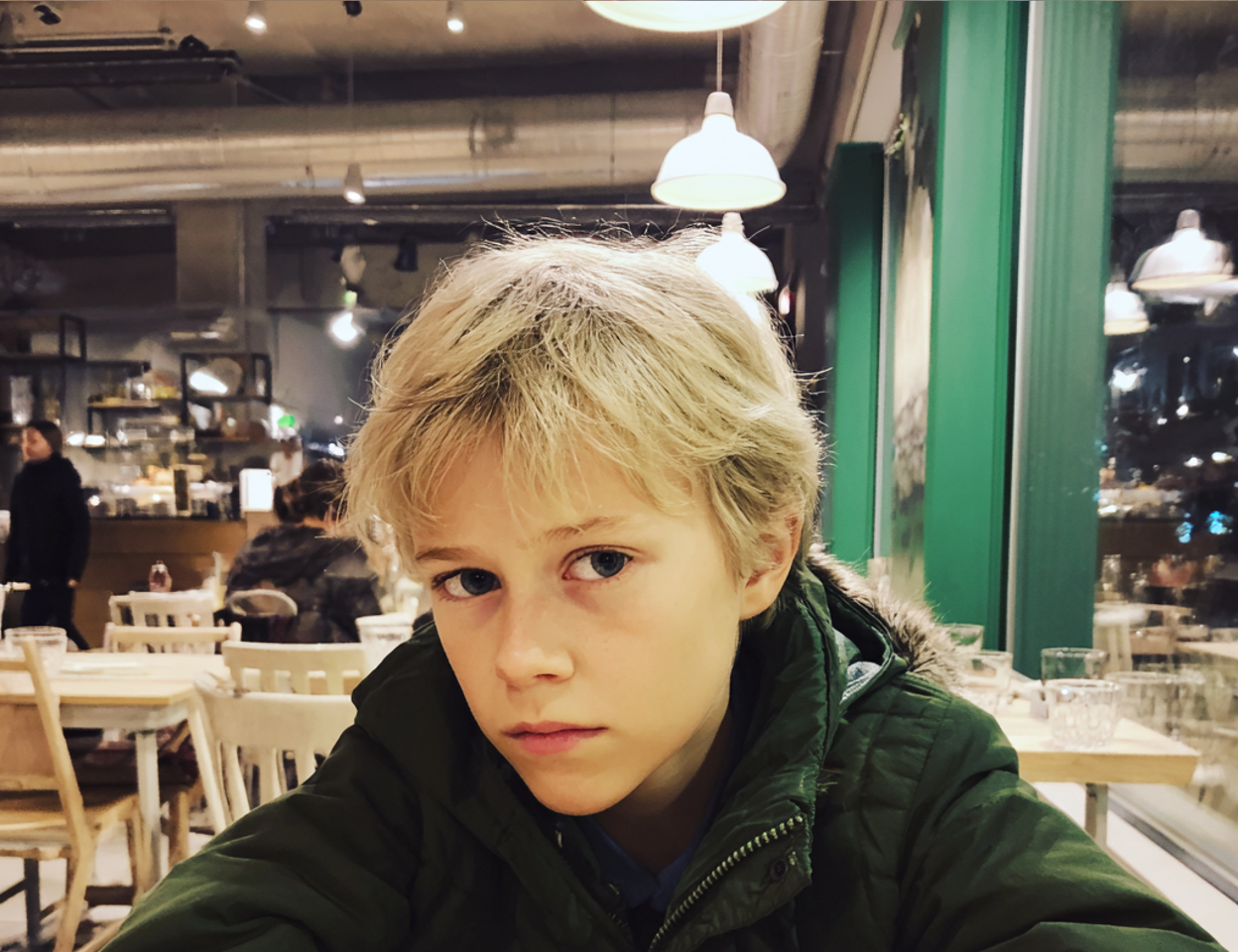 Zbliżenie chłopca siedzącego przy stole | Źródło: Midjourney