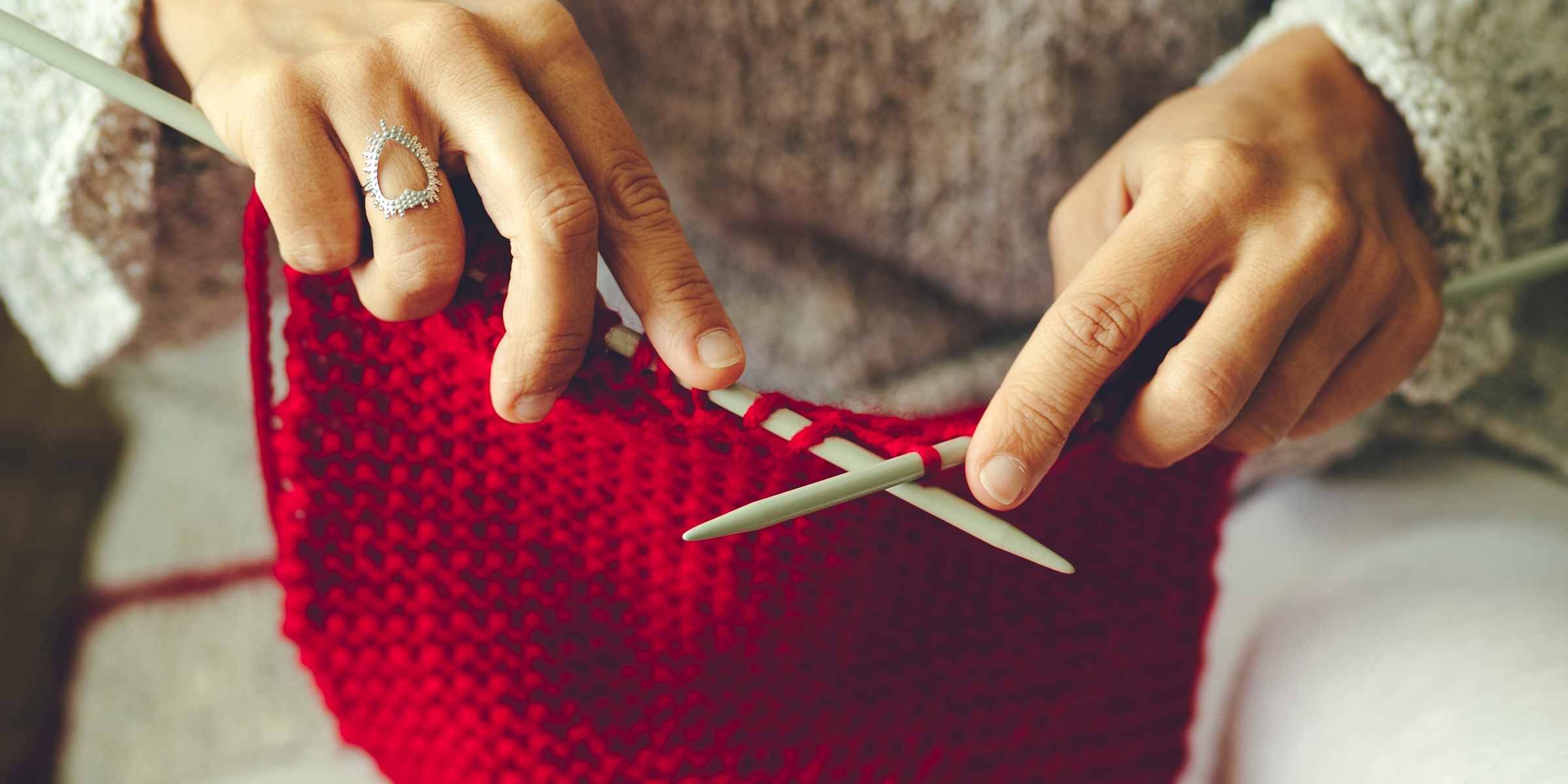 Eine Frau strickt einen roten Pullover | Quelle: Shutterstock