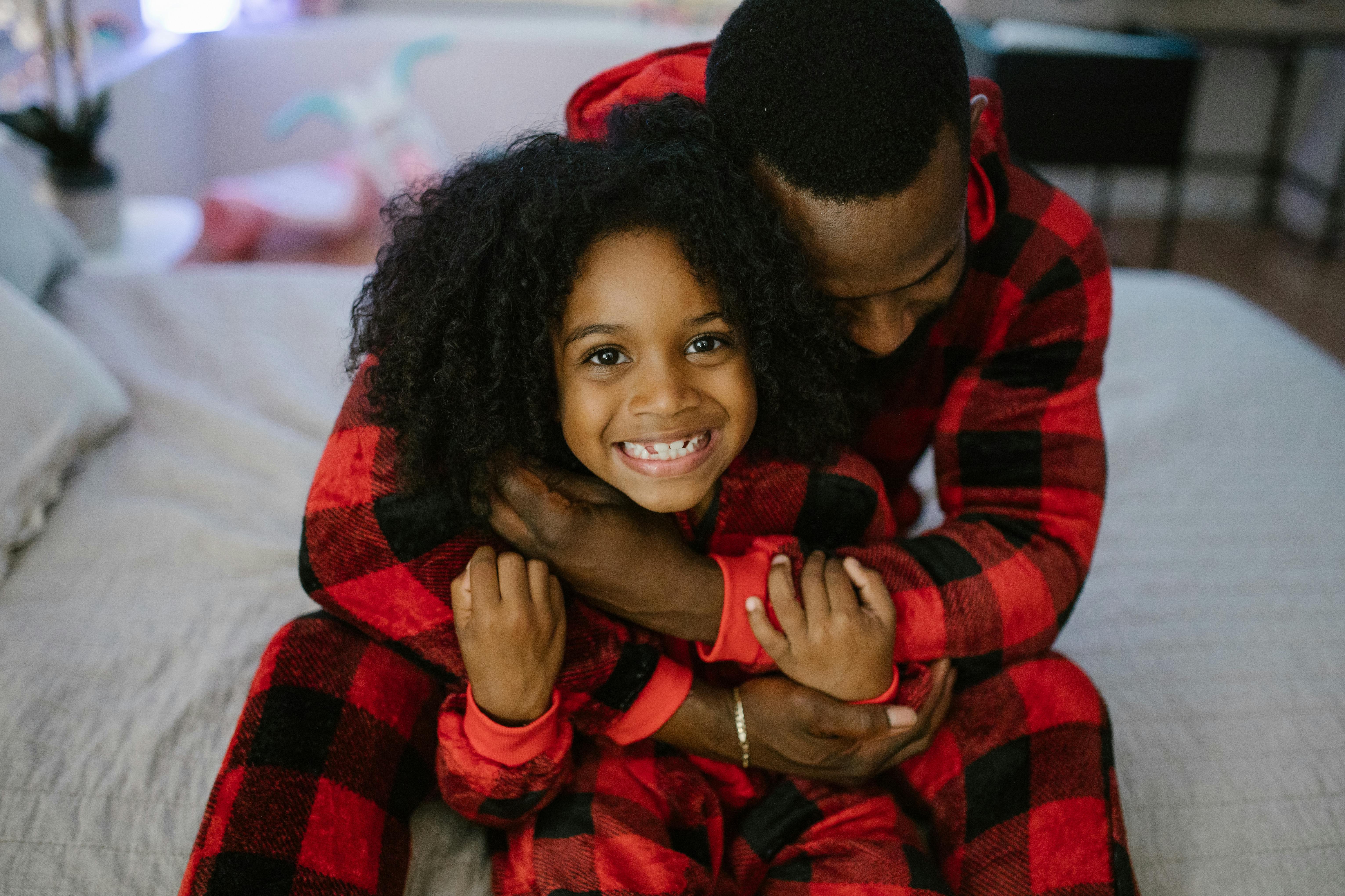 Ein Mann, der seine Tochter umarmt, während er passende Pyjamas trägt | Quelle: Pexels