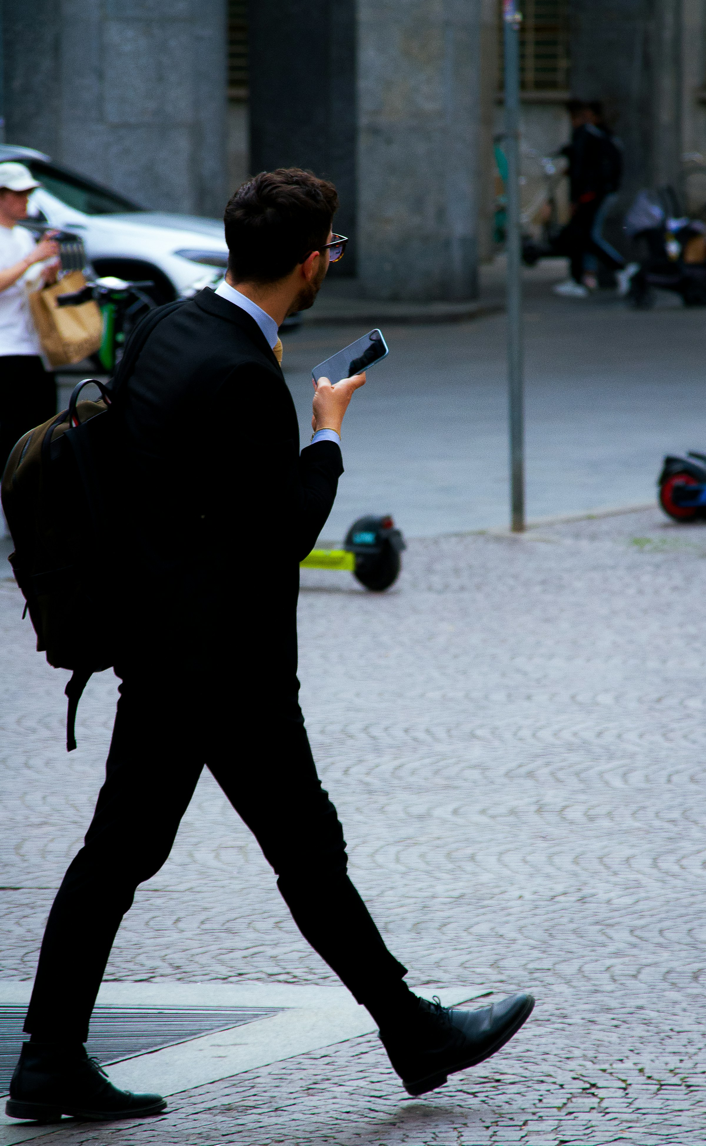 Geschäftsmann auf der Straße mit seinem Handy in der Hand | Quelle: Unsplash