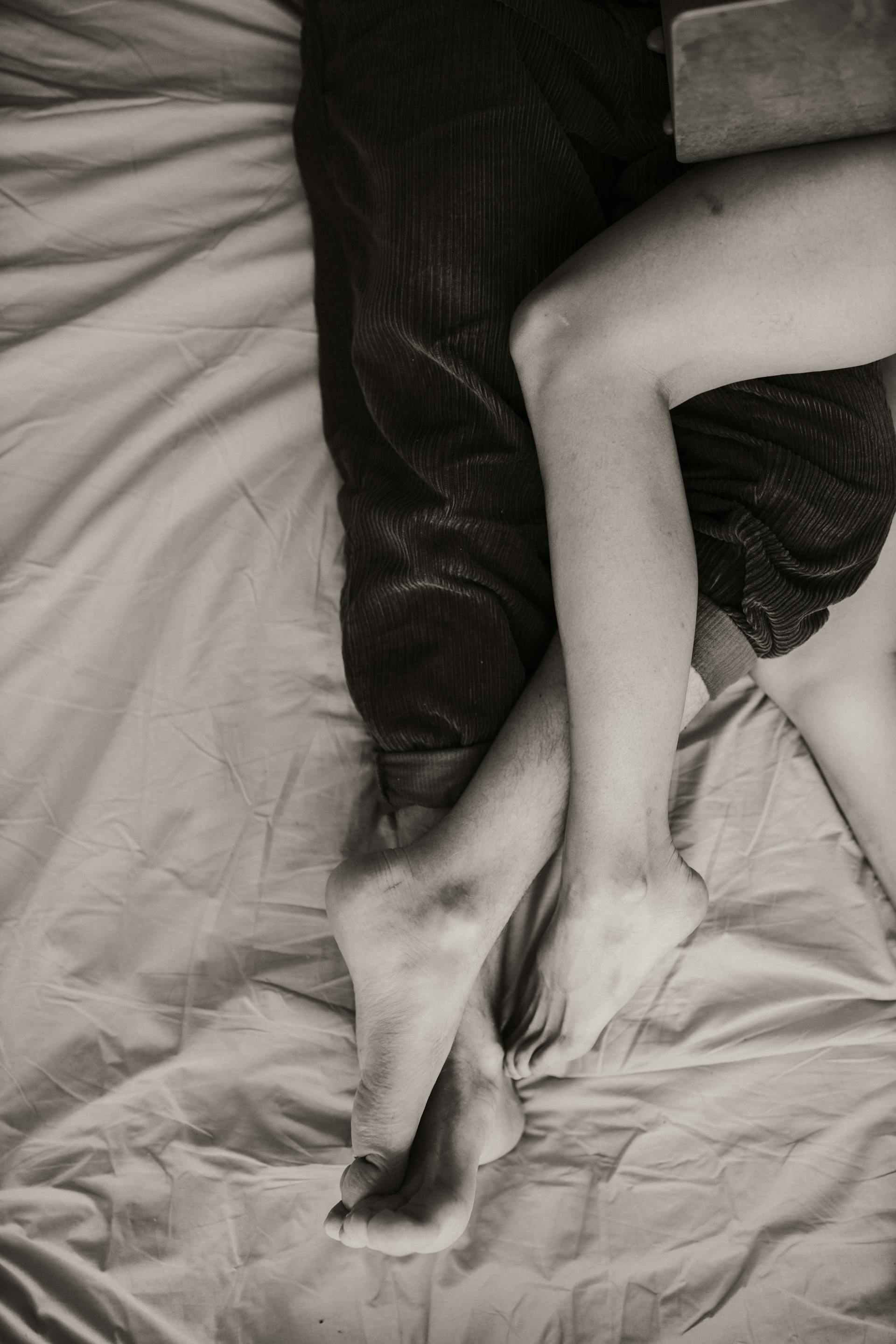 Zwei Menschen liegen auf einem Bett und haben die Beine ineinander verschränkt | Quelle: Pexels