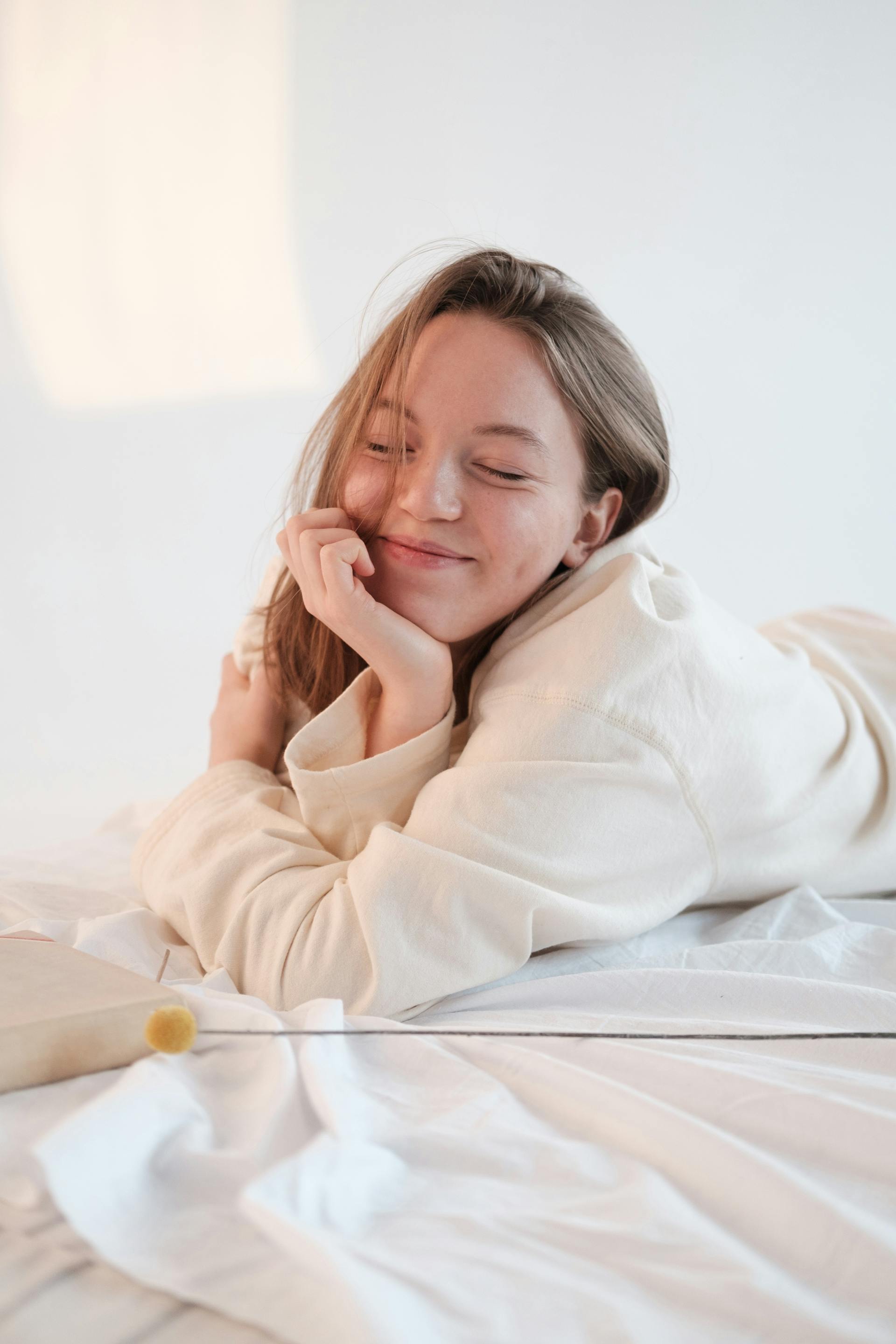 Eine lächelnde Frau, die sich mit geschlossenen Augen im Bett ausruht | Quelle: Pexels