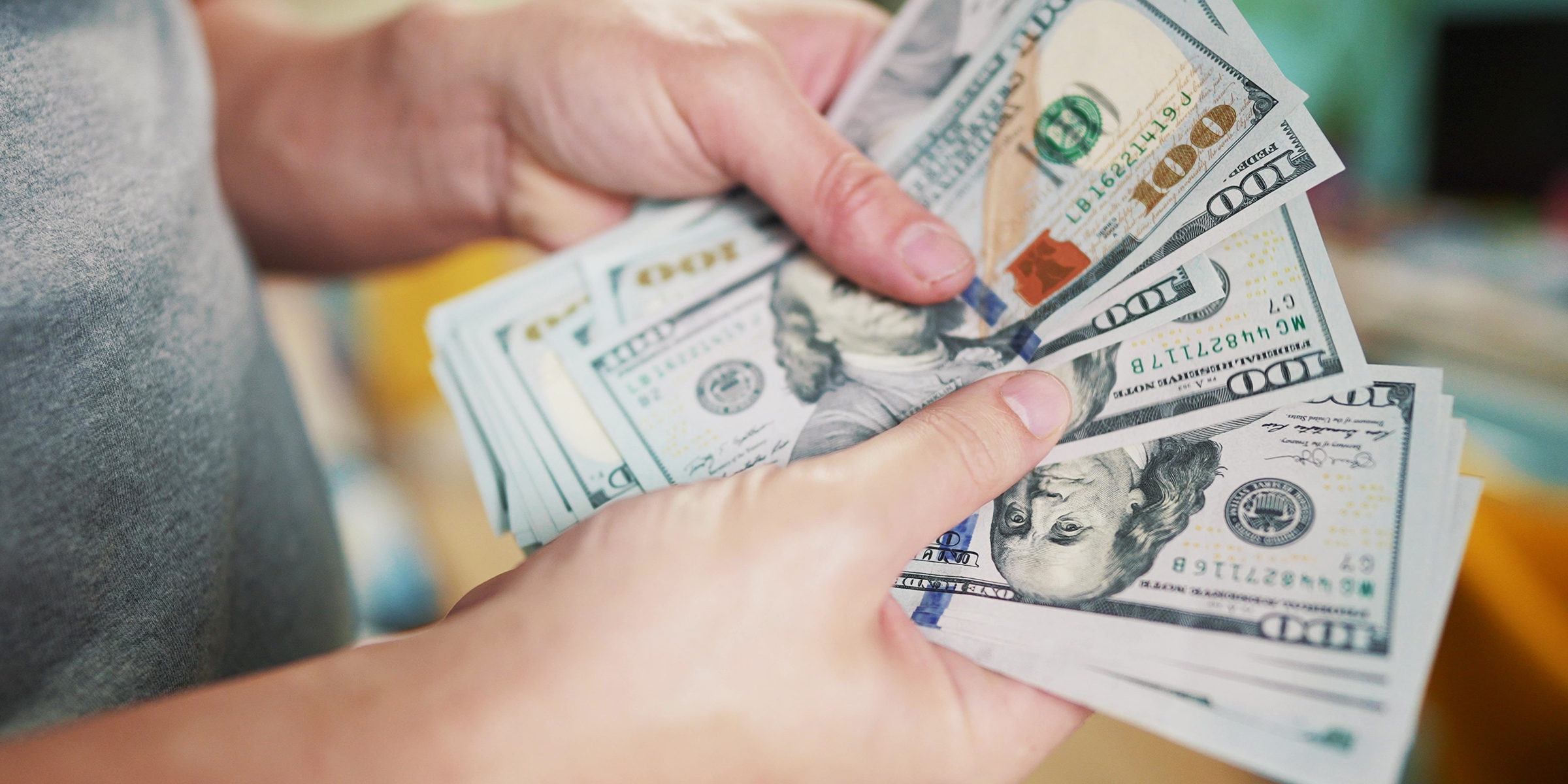 Eine Person, die einen Stapel von 100-Dollar-Scheinen hält und zählt | Quelle: Shutterstock