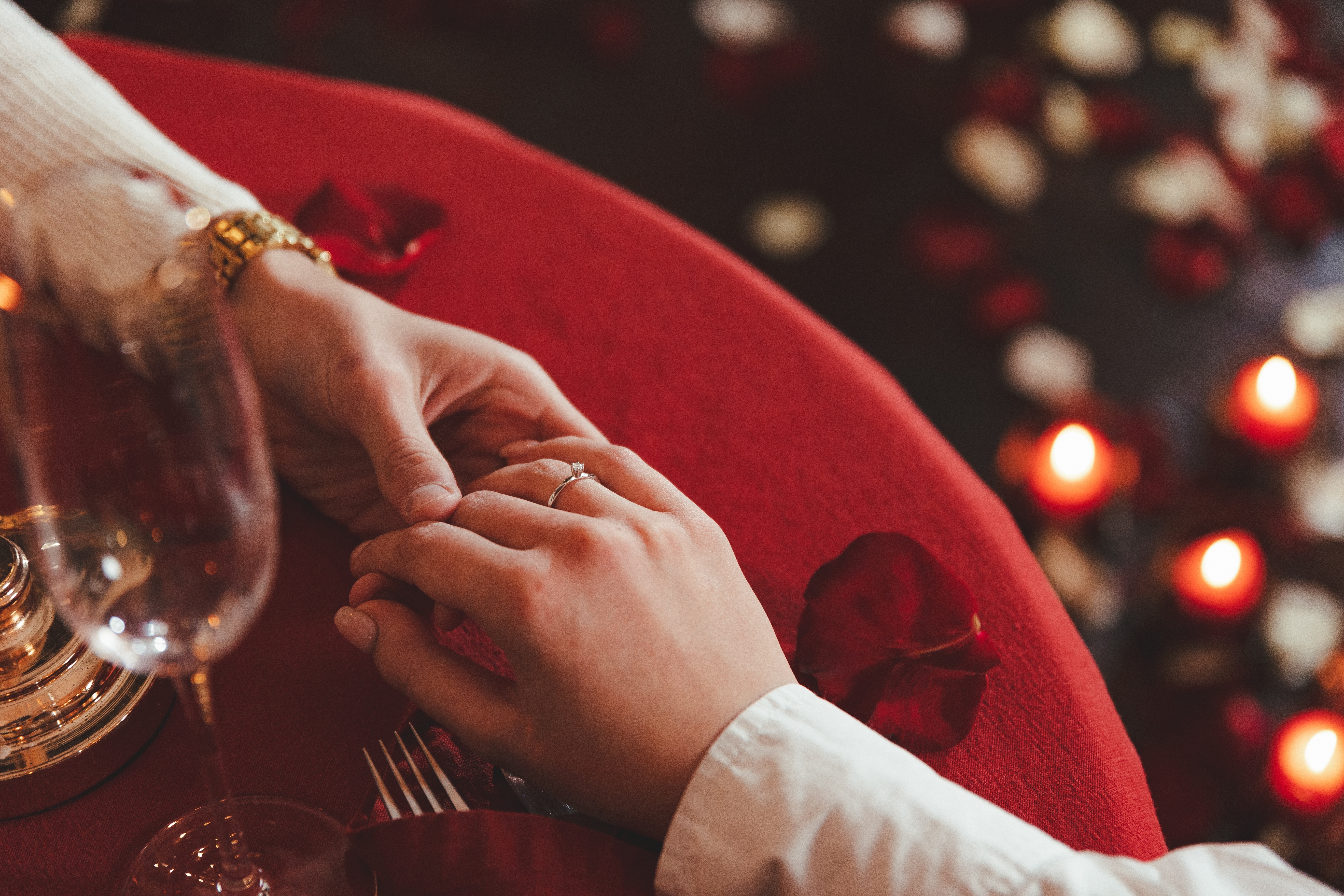 Verlobtes Paar hält beim Abendessen Händchen | Quelle: Shutterstock