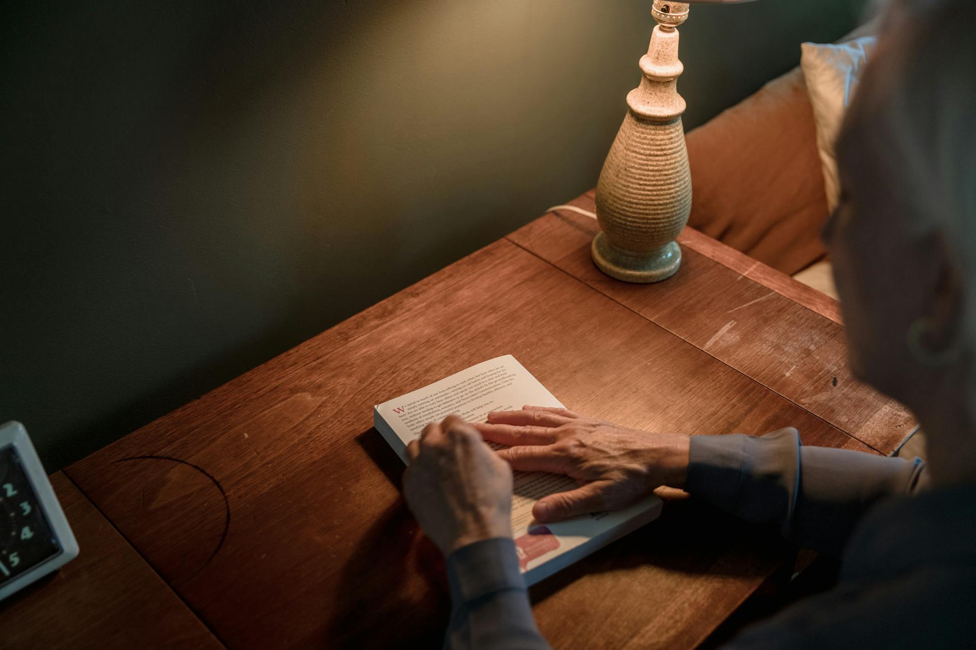 Eine ältere Frau hält ein Buch auf einem Schreibtisch | Quelle: Pexels