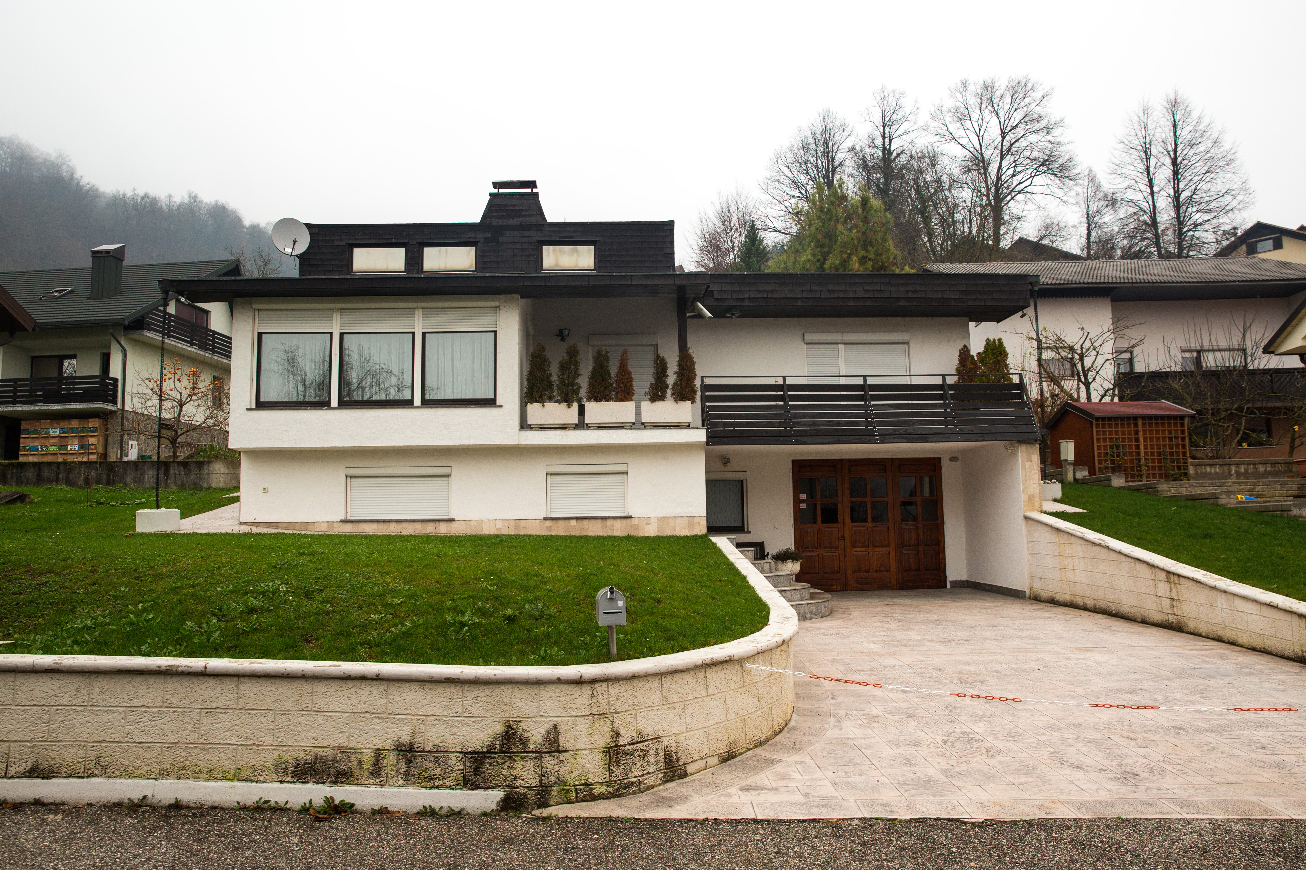Ein Blick von vorne zeigt das ehemalige Elternhaus von Melania Trump in Sevnica, Slowenien, am 27. November 2016, wo sie nach ihrem Umzug aus einem nahegelegenen Wohnblock mit ihren Eltern lebte. Das moderne, zweistöckige Haus mit weißem Putz hat schwarze Zierleisten, einen oberen Balkon mit Topfsträuchern, Rollos und eine gepflasterte Zufahrt zum Innenhof, die von einer niedrigen, geschwungenen Stützmauer begrenzt wird. | Quelle: Getty Images
