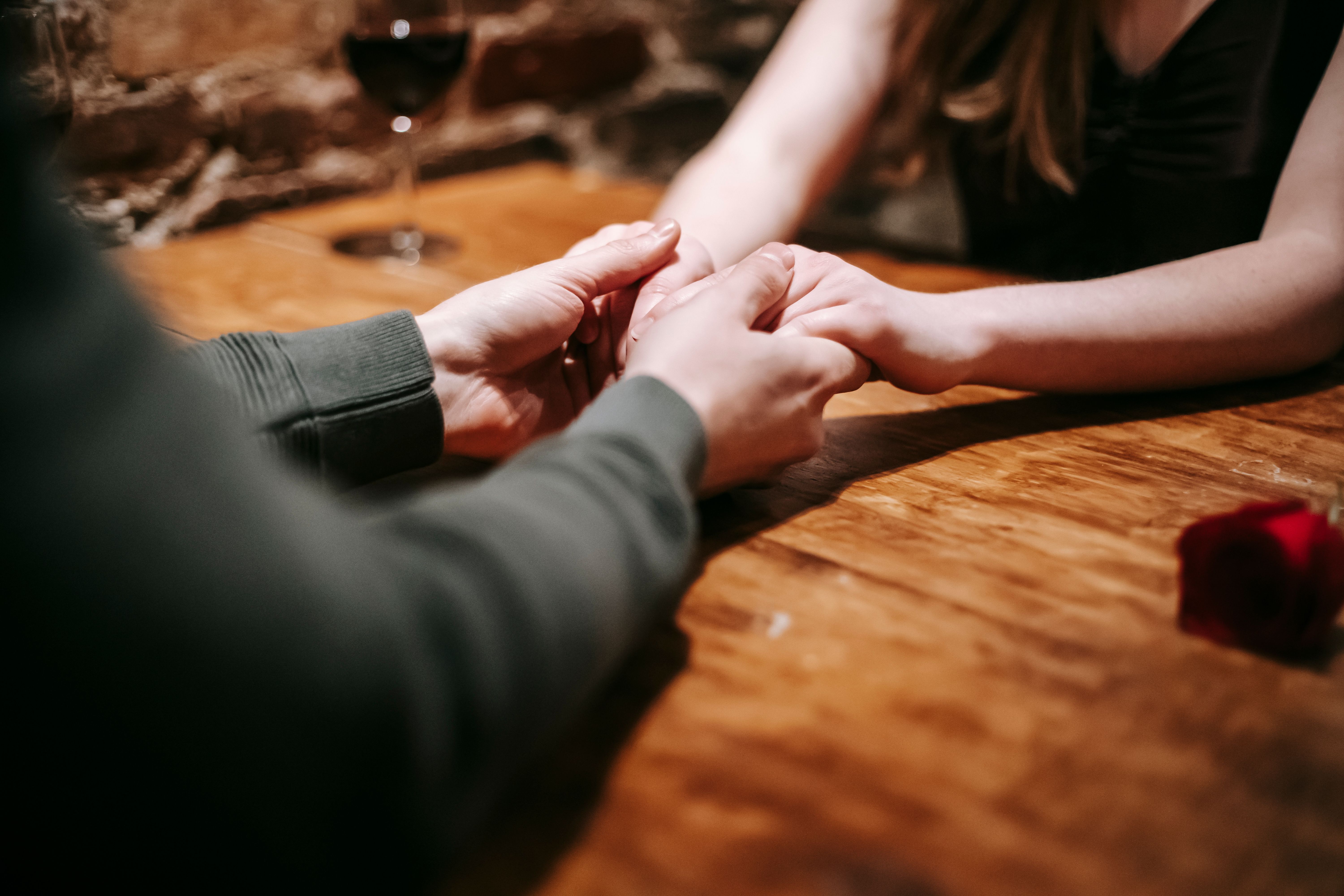 Ein Paar genießt einen romantischen Moment und hält Händchen an einem von Kerzen beleuchteten Tisch in einem gemütlichen Café | Quelle: Pexels