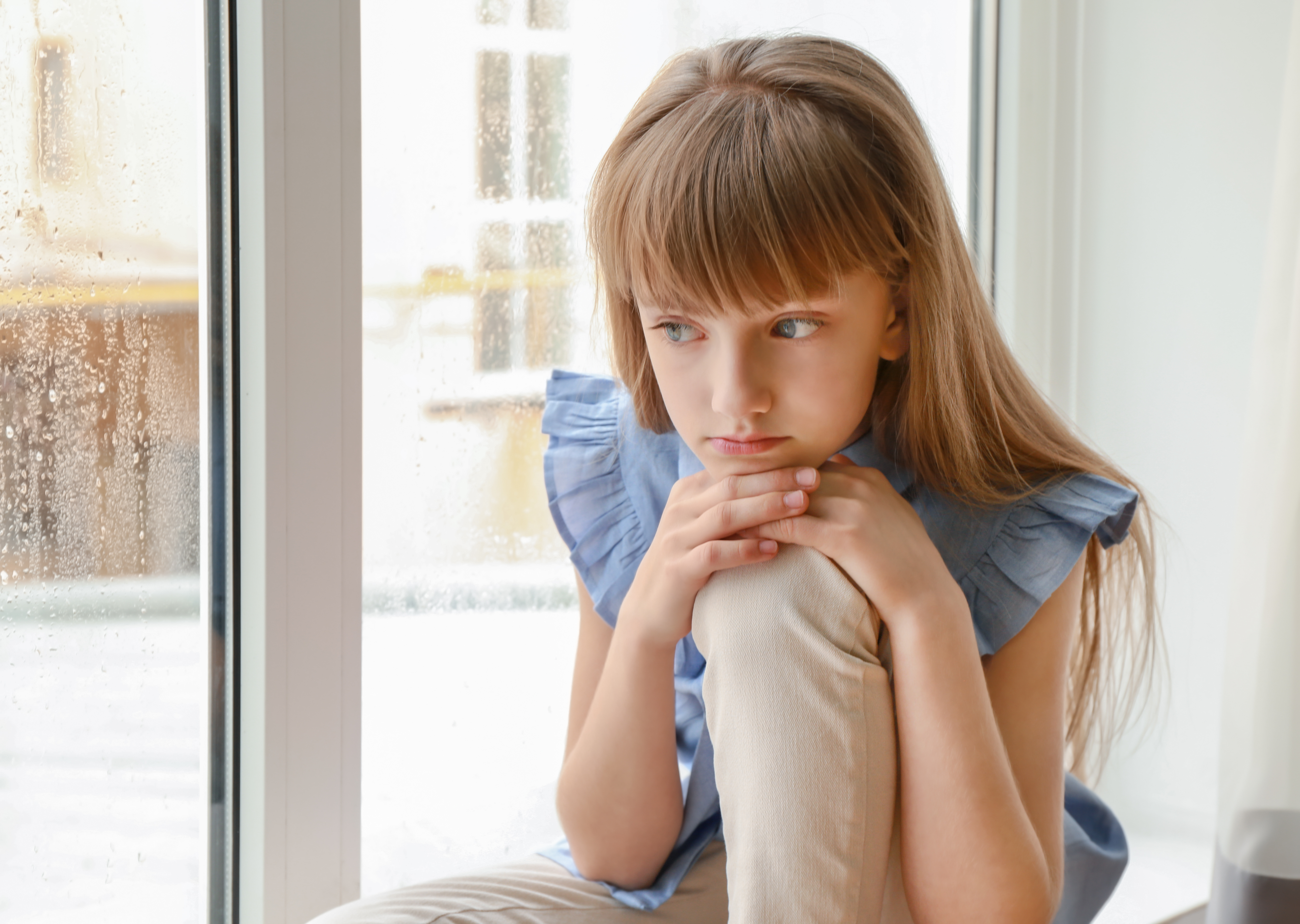 Kleines Mädchen schmollt am Fenster | Quelle: Shutterstock