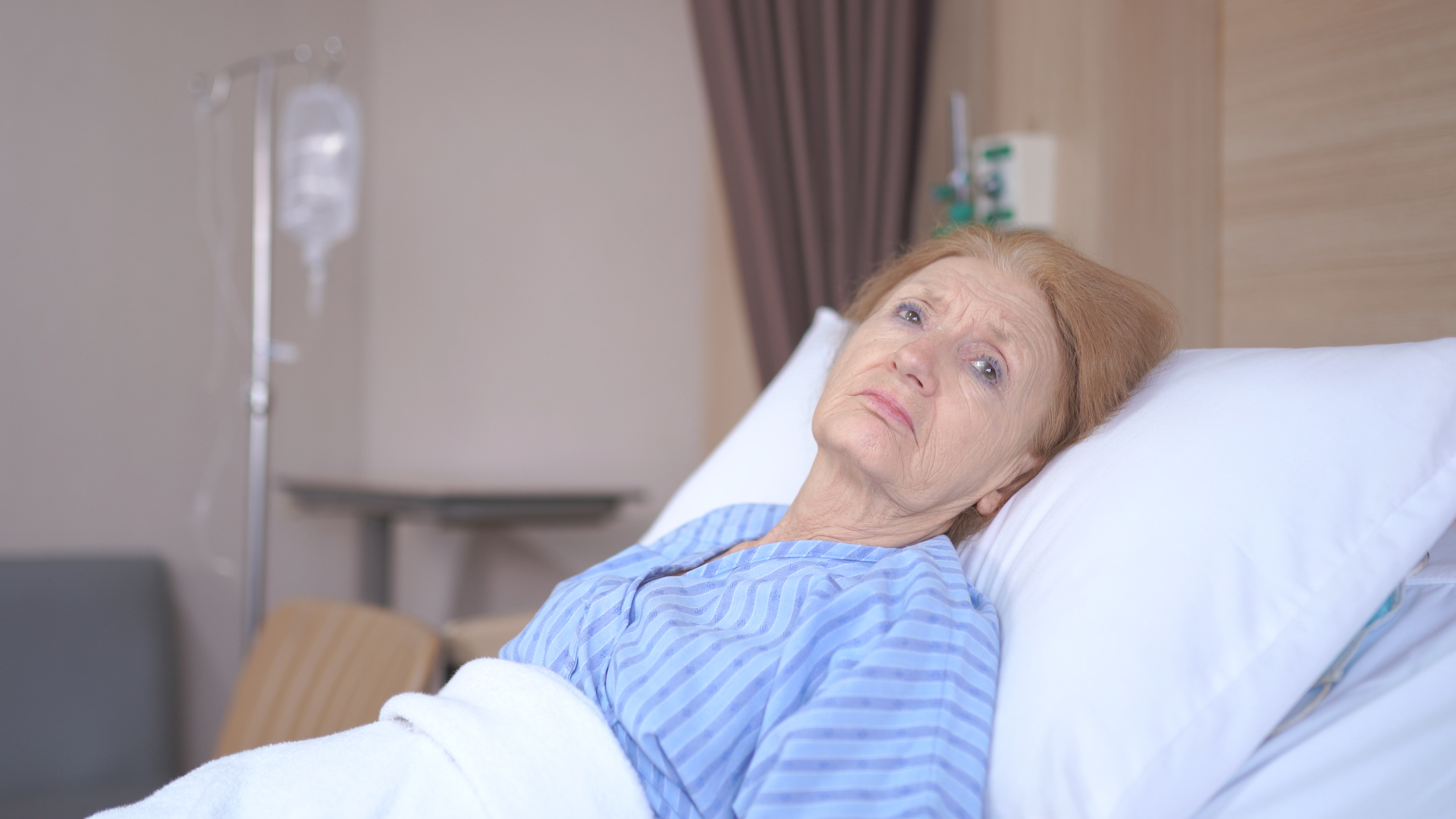 Eine unglückliche ältere Frau in einem Krankenhausbett | Quelle: Shutterstock