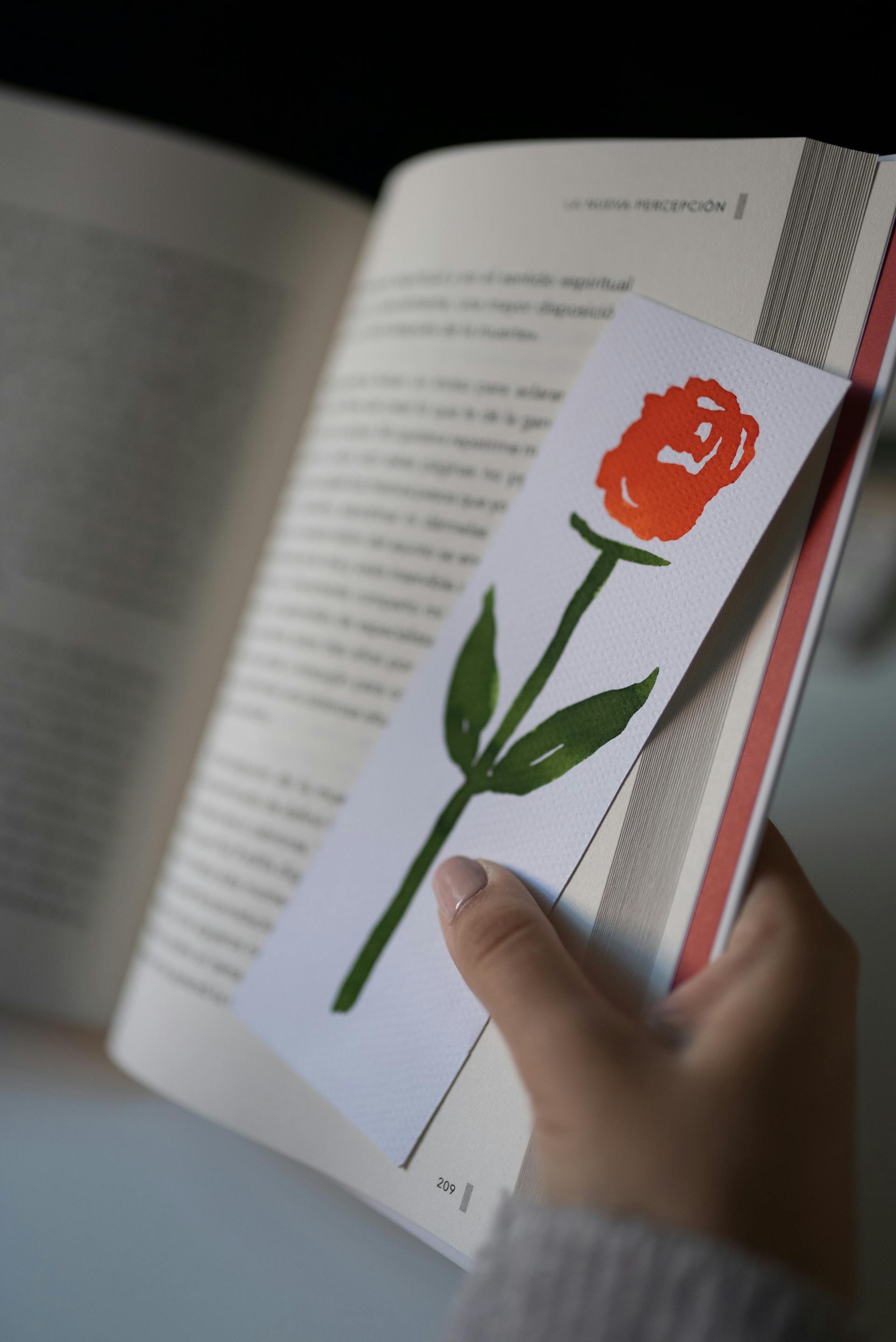 Eine Person hält ein Buch und ein Lesezeichen in der Hand | Quelle: Pexels