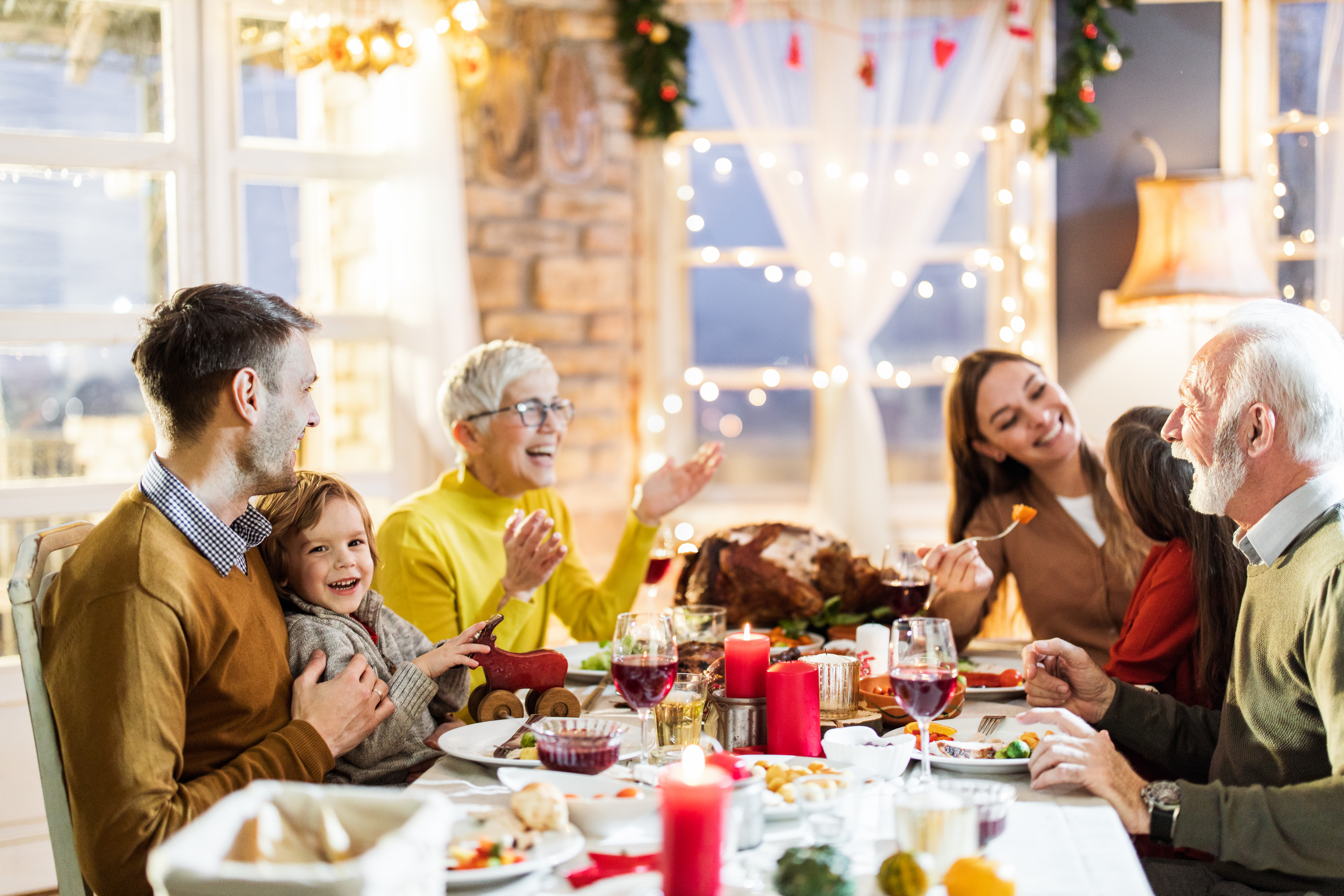 Eine glückliche Mehrgenerationenfamilie unterhält sich während des Thanksgiving-Mittagessens am Esstisch | Quelle: Getty Images