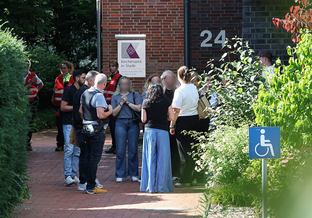 Polizeibeamte stehen zusammen mit Mitarbeitern einer Jugendhilfeeinrichtung und Zeugen in der Nähe des Tatorts, an dem am 29. Juni 2026 bei einer Schießerei in Stade, einer Stadt im Norden Deutschlands etwa 50 Kilometer westlich von Hamburg, sechs Menschen getötet wurden. | Quelle: Getty Images